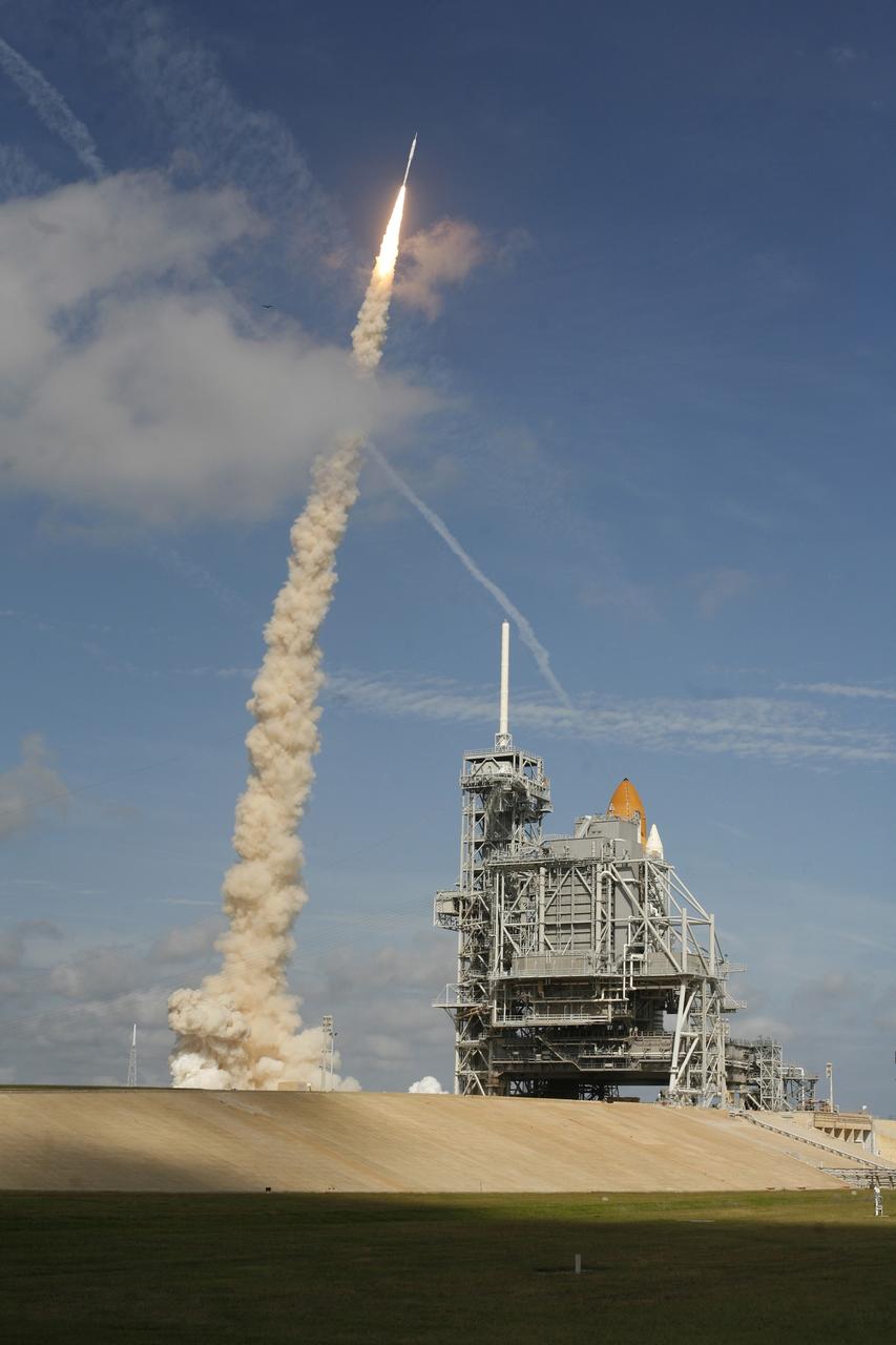 CAPE CANAVERAL, Fla. - With more than 23 times the power output of the Hoover Dam, the Constellation Program's Ares I-X test rocket zooms off Launch Complex 39B at NASA's Kennedy Space Center in Florida.  The rocket produces 2.96 million pounds of thrust at liftoff and reaches a speed of 100 mph in eight seconds.  At right is space shuttle Atlantis, poised on Launch Pad 39A for liftoff, targeted for Nov. 16.    Liftoff of the 6-minute flight test was at 11:30 a.m. EDT Oct. 28. This was the first launch from Kennedy's pads of a vehicle other than the space shuttle since the Apollo Program's Saturn rockets were retired.  The parts used to make the Ares I-X booster flew on 30 different shuttle missions ranging from STS-29 in 1989 to STS-106 in 2000. The data returned from more than 700 sensors throughout the rocket will be used to refine the design of future launch vehicles and bring NASA one step closer to reaching its exploration goals.  For information on the Ares I-X vehicle and flight test, visit http://www.nasa.gov/aresIX.  Photo courtesy of Scott Andrews