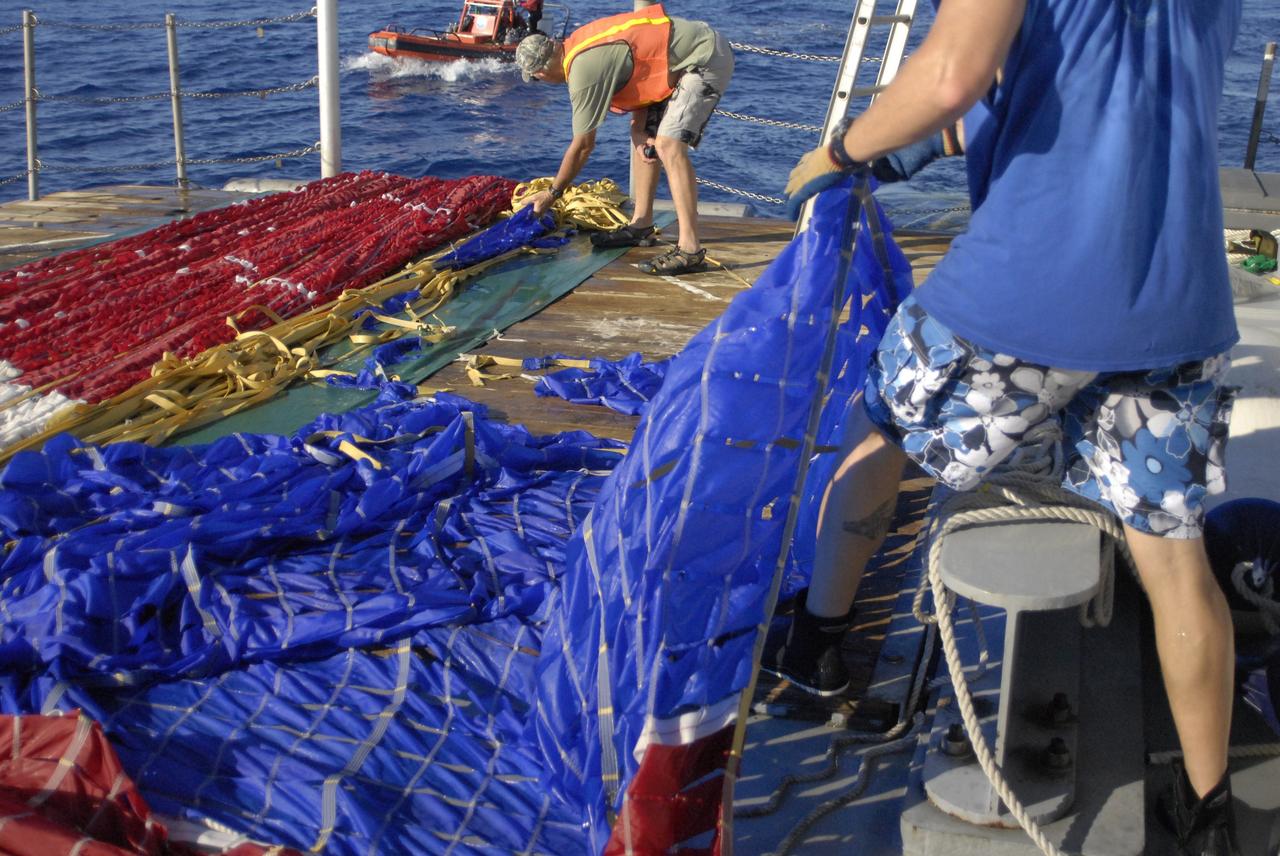 CAPE CANAVERAL, Fla. – In the Atlantic Ocean off the coast of NASA's Kennedy Space Center in Florida, United Space Alliance Recovery Operations personnel pull a colorful main parachute for the Ares I-X rocket onto the deck of the solid rocket booster recovery ship Freedom Star following the launch of the flight test mission.    Liftoff of the 6-minute flight test was at 11:30 a.m. EDT Oct. 28. This was the first launch from Kennedy's pads of a vehicle other than the space shuttle since the Apollo Program's Saturn rockets were retired.  The parts used to make the Ares I-X booster flew on 30 different shuttle missions ranging from STS-29 in 1989 to STS-106 in 2000. The data returned from more than 700 sensors throughout the rocket will be used to refine the design of future launch vehicles and bring NASA one step closer to reaching its exploration goals.  For information on the Ares I-X vehicle and flight test, visit http://www.nasa.gov/aresIX.  Photo credit: United Space Alliance