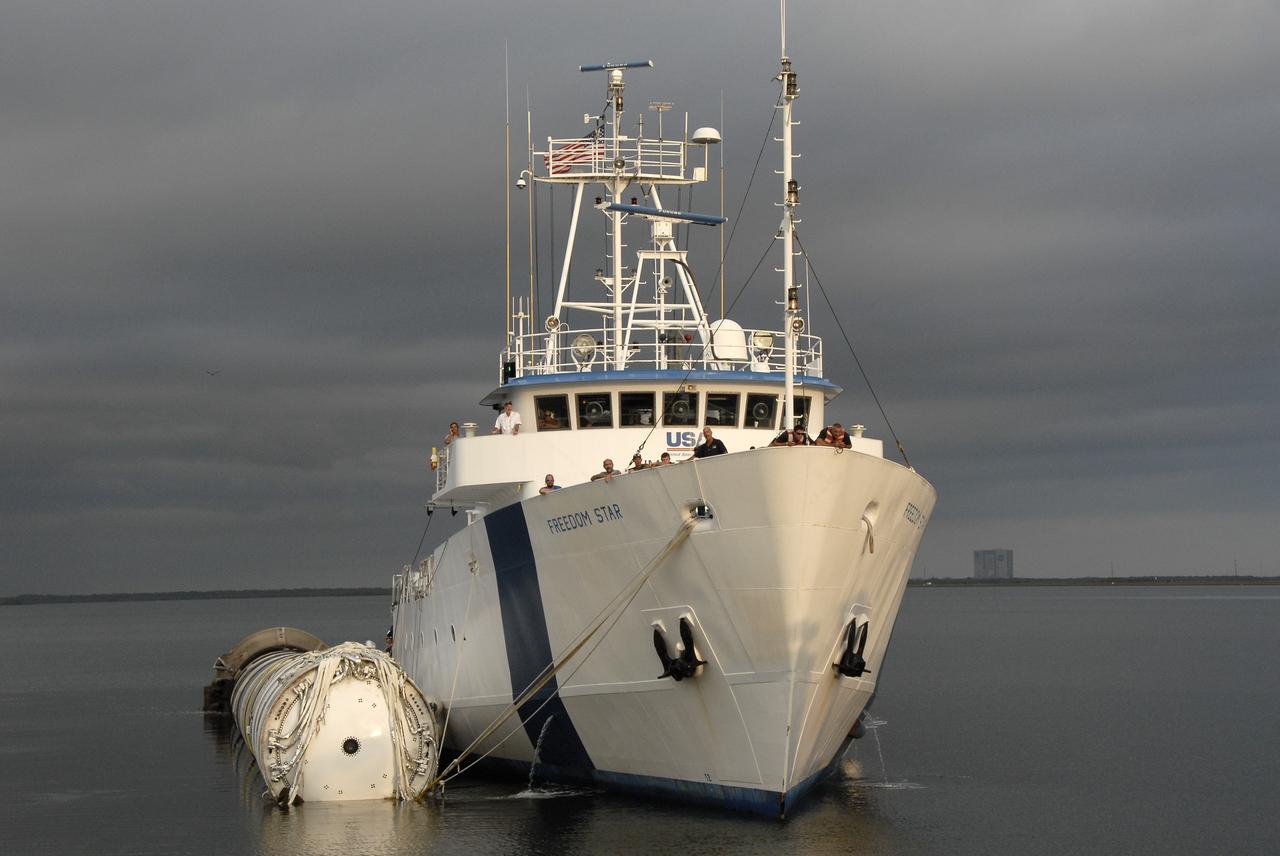 CAPE CANAVERAL, Fla. – The solid rocket booster recovery ship Freedom Star, towing the spent first stage of NASA's Ares I-X rocket, traverses the Banana River along the shore of Cape Canaveral Air Force Station in Florida.  Across the river, in the background, is the Vehicle Assembly Building at NASA's Kennedy Space Center.  Following the launch of the Ares I-X flight test, the booster splashed down in the Atlantic Ocean and was recovered.    Liftoff of the 6-minute flight test was at 11:30 a.m. EDT Oct. 28. This was the first launch from Kennedy's pads of a vehicle other than the space shuttle since the Apollo Program's Saturn rockets were retired.  The parts used to make the Ares I-X booster flew on 30 different shuttle missions ranging from STS-29 in 1989 to STS-106 in 2000. The data returned from more than 700 sensors throughout the rocket will be used to refine the design of future launch vehicles and bring NASA one step closer to reaching its exploration goals.  For information on the Ares I-X vehicle and flight test, visit http://www.nasa.gov/aresIX.  Photo credit: NASA/Kim Shiflett