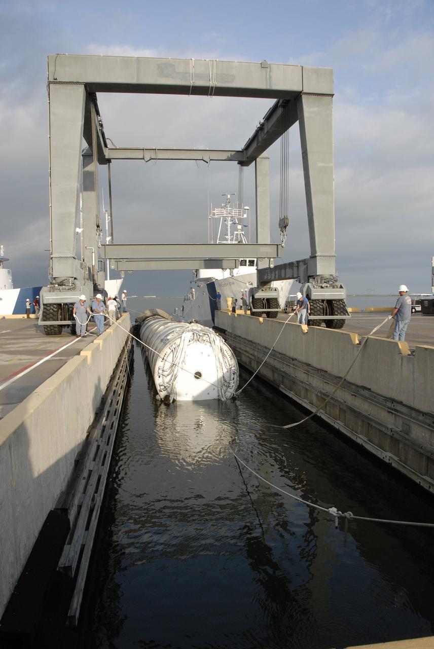 CAPE CANAVERAL, Fla. – At Hangar AF on Cape Canaveral Air Force Station in Florida, workers guide the spent first stage of NASA's Ares I-X rocket into a slip.  The solid rocket booster recovery ship Freedom Star, in the background, recovered the booster after it splashed down in the Atlantic Ocean following its flight test.    Liftoff of the 6-minute flight test was at 11:30 a.m. EDT Oct. 28. This was the first launch from Kennedy's pads of a vehicle other than the space shuttle since the Apollo Program's Saturn rockets were retired.  The parts used to make the Ares I-X booster flew on 30 different shuttle missions ranging from STS-29 in 1989 to STS-106 in 2000. The data returned from more than 700 sensors throughout the rocket will be used to refine the design of future launch vehicles and bring NASA one step closer to reaching its exploration goals.  For information on the Ares I-X vehicle and flight test, visit http://www.nasa.gov/aresIX.  Photo credit: NASA/Kim Shiflett