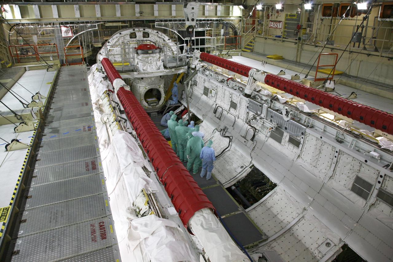 CAPE CANAVERAL, Fla. - In Orbiter Processing Facility Bay 3 at NASA's Kennedy Space Center in Florida, United Space Alliance workers guide a "fish pole" lifting fixture being lowered by crane toward space shuttle Discovery's payload bay. The fixture will be used to remove the gaseous nitrogen tank during processing for the shuttle's STS-131 mission to the International Space Station. The tanks are used for atmosphere conditioning and for moving potable water in the crew module. The seven-member STS-131 crew will deliver a Multi-Purpose Logistics Module filled with science racks to be transferred to laboratories on the station. Three spacewalks will include work to attach a spare ammonia tank assembly to the station's exterior and return a European experiment from outside the station's Columbus module. This will be the 33rd shuttle mission to the station. Launch is targeted for March 18, 2010. Photo credit: NASA/Troy Cryder