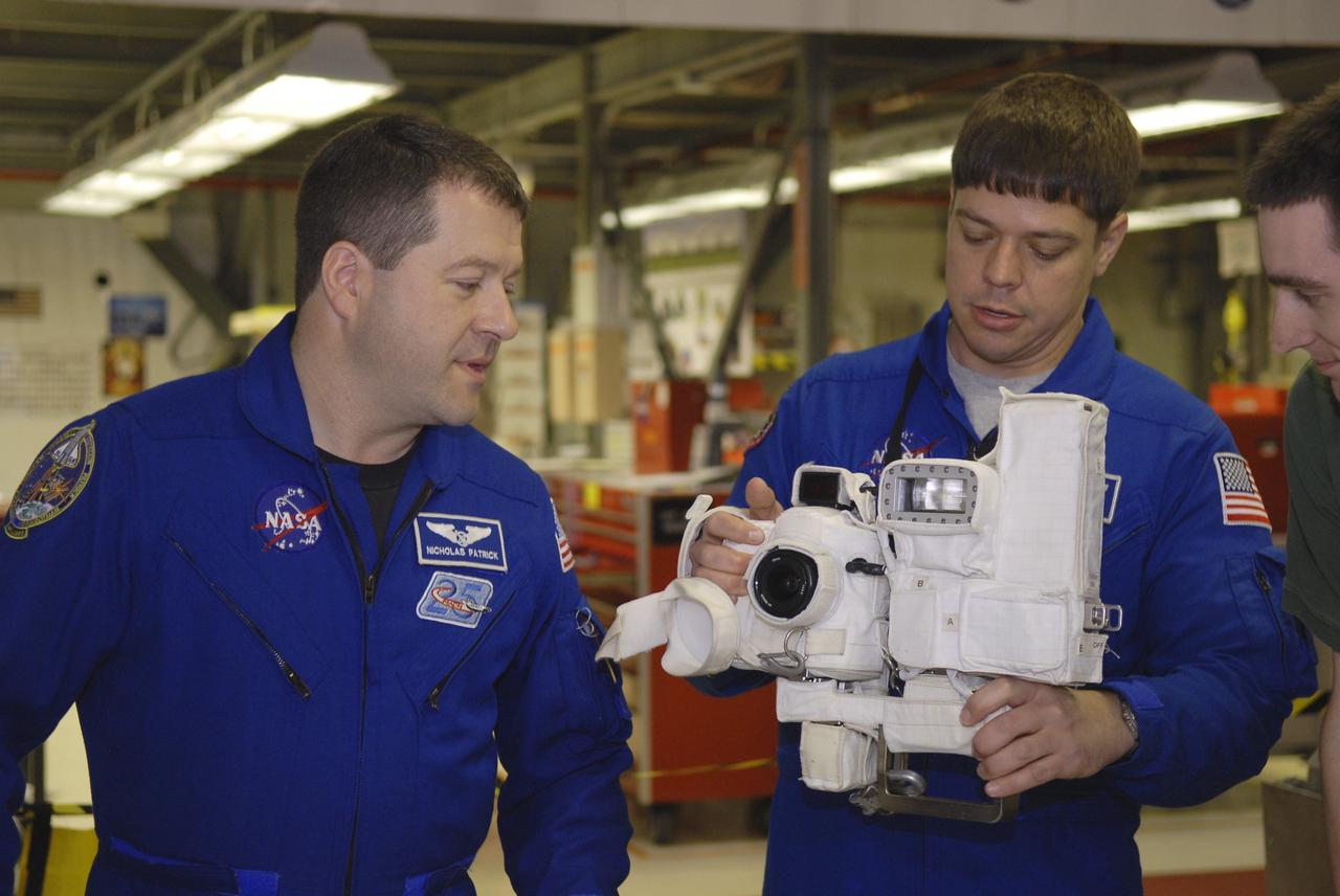CAPE CANAVERAL, Fla. – In Orbiter Processing Facility-3 at NASA's Kennedy Space Center in Florida, STS-130 Mission Specialist Nicolas Patrick, left, discusses the operation of a camera that will fly on space shuttle Endeavour with his crewmate, Mission Specialist Robert Behnken.    The crew is at Kennedy for a crew equipment interface test, or CEIT, which provides hands-on training and observation of shuttle and flight hardware.  The STS-130 flight will carry the Tranquility pressurized module with a built-in cupola to the International Space Station aboard Endeavour.  Launch is targeted for Feb. 4, 2010. Photo credit: NASA/Kim Shiflett
