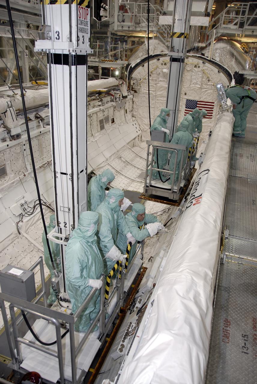 CAPE CANAVERAL, Fla. – In Orbiter Processing Facility-3 at NASA's Kennedy Space Center in Florida, members of the STS-130 crew check out the placement of the Canadian-built robotic arm in space shuttle Endeavour's payload bay.    The crew is at Kennedy for a crew equipment interface test, or CEIT, which provides hands-on training and observation of shuttle and flight hardware.  The STS-130 flight will carry the Tranquility pressurized module with a built-in cupola to the International Space Station aboard Endeavour.  Launch is targeted for Feb. 4, 2010. Photo credit: NASA/Kim Shiflett