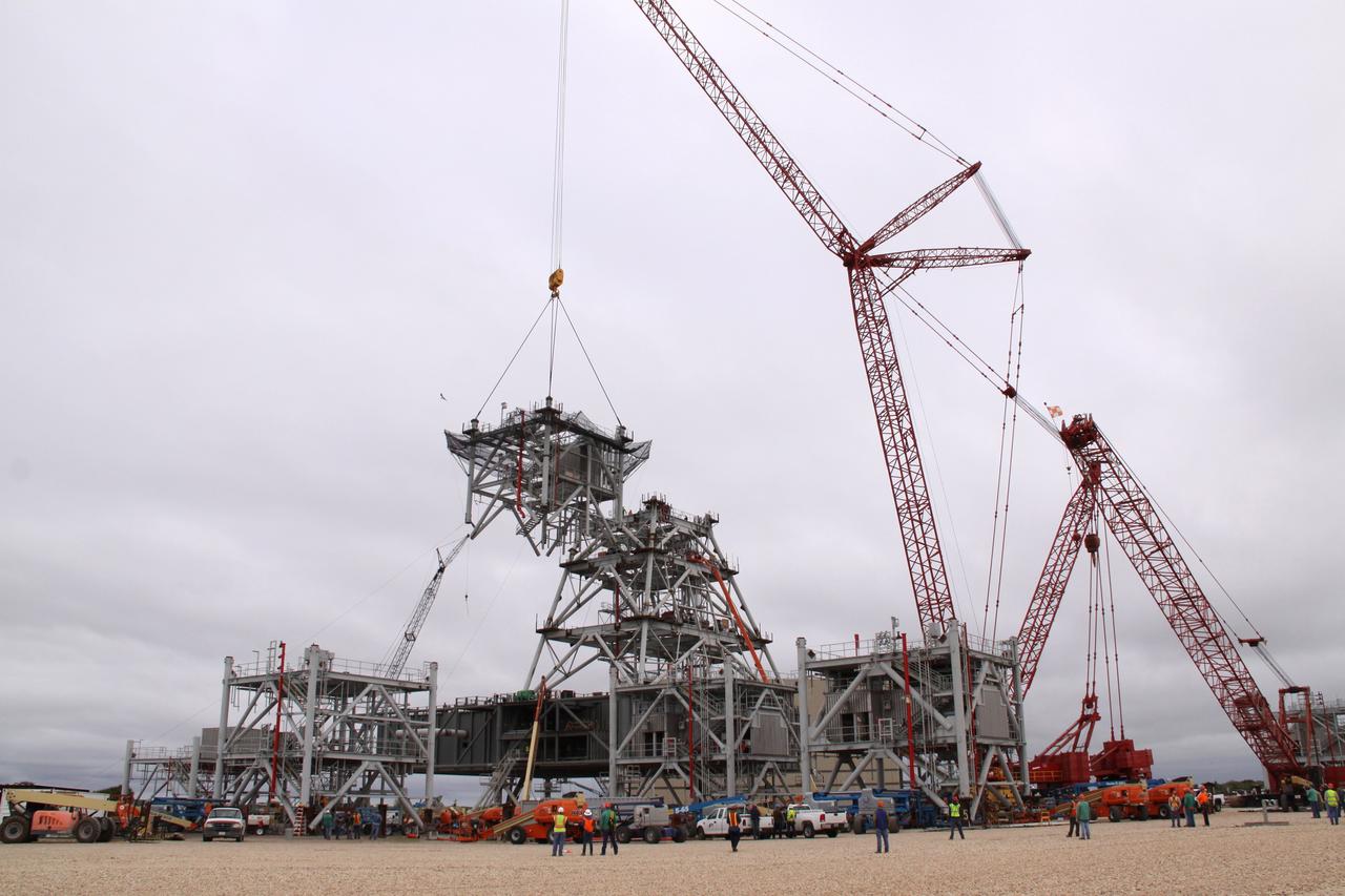 CAPE CANAVERAL, Fla. – At NASA's Kennedy Space Center in Florida, a crane lifts a fourth tower section toward three sections already secured to a new mobile launcher, or ML, being constructed to support the Constellation Program. The tower will be approximately 345 feet tall when completed and have multiple platforms for personnel access. The ML is being built at the mobile launcher park site area north of Kennedy's Vehicle Assembly Building. The launcher will provide a base to launch the Ares I, designed to transport the Orion crew exploration vehicle, its crew and cargo to low Earth orbit. The base is being made lighter than space shuttle mobile launcher platforms so the crawler-transporter can pick up the heavier load of the tower and taller rocket. For information on the Ares I, visit http://www.nasa.gov/ares. Photo credit: NASA/Jack Pfaller