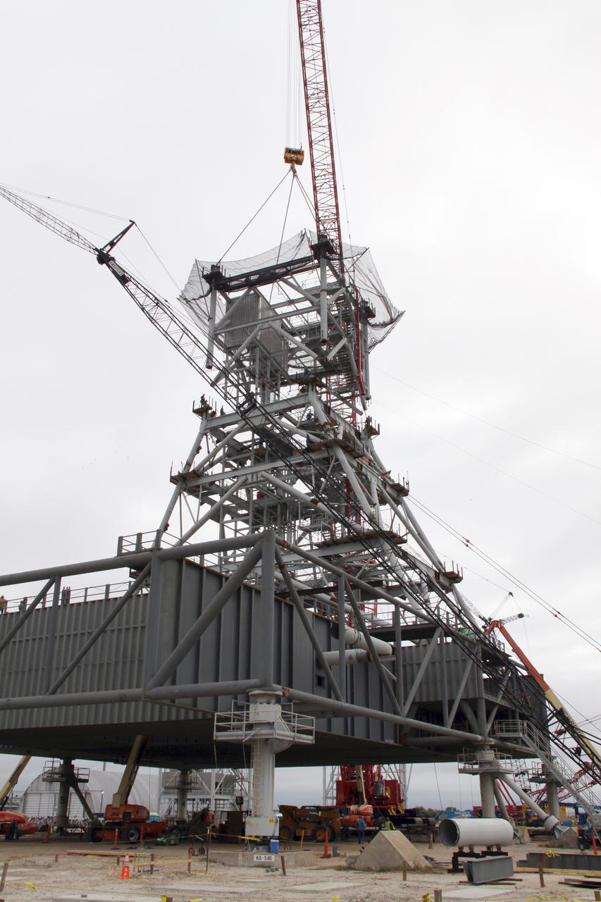 CAPE CANAVERAL, Fla. – At NASA's Kennedy Space Center in Florida, a crane lowers a fourth tower section onto three sections already secured to a new mobile launcher, or ML, being constructed to support the Constellation Program. The tower will be approximately 345 feet tall when completed and have multiple platforms for personnel access. The ML is being built at the mobile launcher park site area north of Kennedy's Vehicle Assembly Building. The launcher will provide a base to launch the Ares I, designed to transport the Orion crew exploration vehicle, its crew and cargo to low Earth orbit. The base is being made lighter than space shuttle mobile launcher platforms so the crawler-transporter can pick up the heavier load of the tower and taller rocket. For information on the Ares I, visit http://www.nasa.gov/ares. Photo credit: NASA/Jack Pfaller