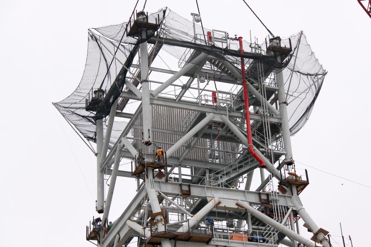 CAPE CANAVERAL, Fla. – At NASA's Kennedy Space Center in Florida, workers guide a fourth tower section into position onto three sections already secured to a new mobile launcher, or ML, being constructed to support the Constellation Program. The tower will be approximately 345 feet tall when completed and have multiple platforms for personnel access. The ML is being built at the mobile launcher park site area north of Kennedy's Vehicle Assembly Building. The launcher will provide a base to launch the Ares I, designed to transport the Orion crew exploration vehicle, its crew and cargo to low Earth orbit. The base is being made lighter than space shuttle mobile launcher platforms so the crawler-transporter can pick up the heavier load of the tower and taller rocket. For information on the Ares I, visit http://www.nasa.gov/ares. Photo credit: NASA/Jack Pfaller