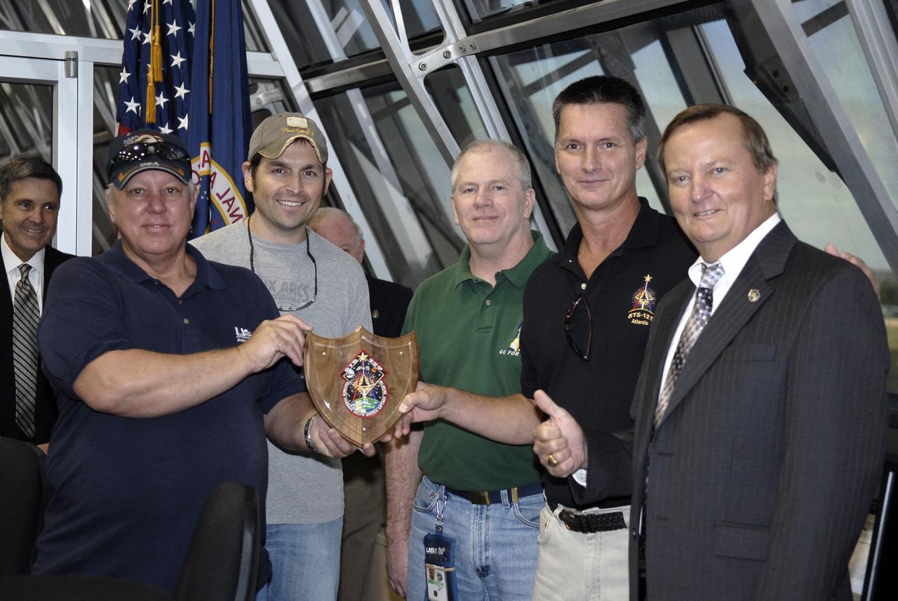 CAPE CANAVERAL, Fla. - In Firing Room 4 of NASA Kennedy Space Center's Launch Control Center, NASA's space shuttle launch director Michael Leinbach presents members of the United Space Alliance Midbody Team for space shuttle Atlantis with the Launch Director's Flow Award, a plaque emblazoned with the logo for Atlantis' STS-129 mission.  The award recognizes the team's superior work in reconfiguring the shuttle's payload bay between STS-125, the last Hubble Space Telescope servicing mission, and the current STS-129 mission to the International Space Station.  From left are midbody lead Jim Reed, midbody thermal control system technician Chris Oliver, midbody planner and payload operations representative for STS-129 Steve Durnin, Orbiter Processing Facility-1 midbody supervisor Bobby Pracek, and Leinbach.    Liftoff of Atlantis from Launch Pad 39A on its STS-129 mission to the International Space Station came at 2:28 p.m. EST Nov. 16.  For information on the STS-129 mission and crew, visit http://www.nasa.gov/mission_pages/shuttle/shuttlemissions/sts129/index.html. Photo credit: NASA/Kim Shiflett