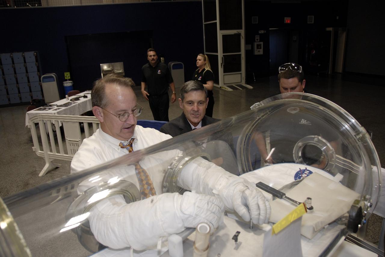 CAPE CANAVERAL, Fla. – At the Astronaut Hall of Fame near NASA’s Kennedy Space Center in Florida, Patrick Simpkins, director of Engineering at Kennedy, tries out a pair of space gloves for their dexterity and flexibility in a glove box  at the 2009 Astronaut Glove Challenge, part of NASA’s Centennial Challenges Program.  Looking over his shoulder is Kennedy Director Bob Cabana.    The nationwide competition focused on developing improved pressure suit gloves for astronauts to use while working in space.  During the challenge, the gloves were submitted to burst tests, joint force tests and tests to measure their dexterity and strength during operation in a glove box which simulates the vacuum of space.  Centennial Challenges is NASA’s program of technology prizes for the citizen-inventor. The winning prize for the Glove Challenge is $250,000 provided by the Centennial Challenges Program.  Photo credit: NASA/Kim Shiflett