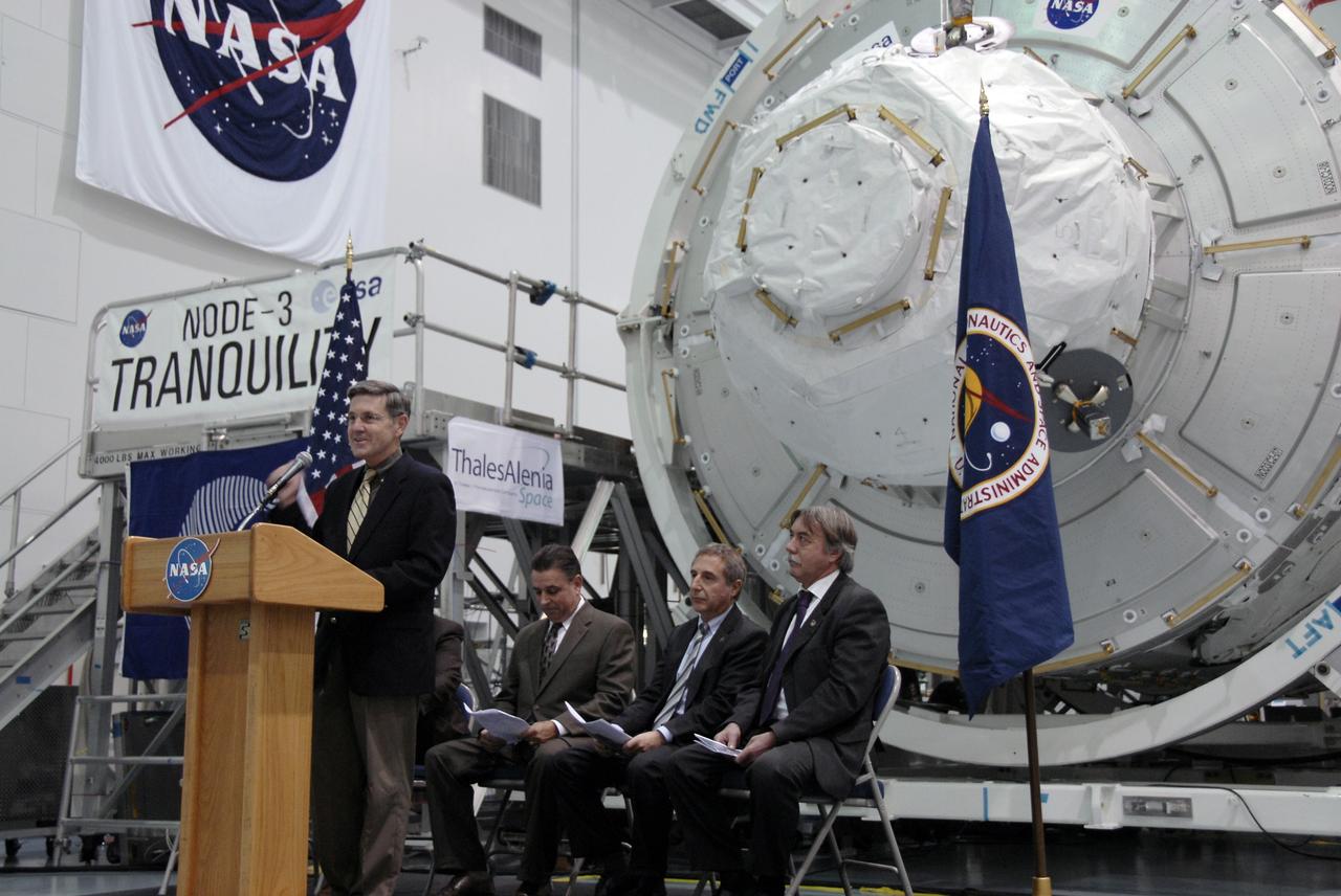 CAPE CANAVERAL, Fla. – In the Space Station Processing Facility at NASA's Kennedy Space Center in Florida, Kennedy Director Bob Cabana addresses the invited guests at a ceremony transferring the ownership of node 3 for the International Space Station, looming in the background, from the European Space Agency, or ESA, to NASA.  Seated, from left, are William Dowdell, deputy for Operations, International Space Station and Spacecraft Processing, Kennedy; Bernardo Patti, head of International Space Station, Program Department, ESA; and Secondino Brondolo, head of the Space Infrastructure, Thales Alenia Space Italy.    Node 3 is named "Tranquility" after the Sea of Tranquility, the lunar landing site of Apollo 11.  The payload for the STS-130 mission, Tranquility is a pressurized module that will provide room for many of the International Space Station's life support systems. The module was built for ESA by Thales Alenia Space in Turin, Italy. Attached to one end of Tranquility is a cupola, a unique work station with six windows on its sides and one on top.  The cupola resembles a circular bay window and will provide a vastly improved view of the station's exterior. Just under 10 feet in diameter, the module will accommodate two crew members and portable workstations that can control station and robotic activities. The multi-directional view will allow the crew to monitor spacewalks and docking operations, as well as provide a spectacular view of Earth and other celestial objects. Space shuttle Endeavour's STS-130 mission is targeted to launch Feb. 4, 2010. Photo credit: NASA/Kim Shiflett