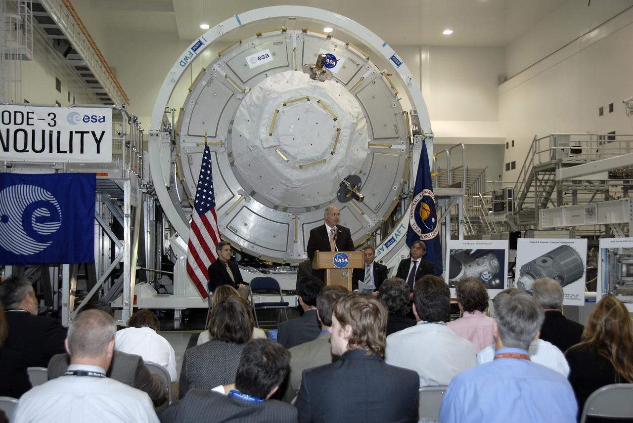 CAPE CANAVERAL, Fla. – In the Space Station Processing Facility at NASA's Kennedy Space Center in Florida, Michael Suffredini, program manager, International Space Station, NASA, addresses the invited guests at a ceremony transferring the ownership of node 3 for the International Space Station, looming in the background, from the European Space Agency, or ESA, to NASA.  Seated, from left, are Bob Cabana, Kennedy Space Center director; Bernardo Patti, head of International Space Station, Program Department, ESA; and Secondino Brondolo, head of the Space Infrastructure, Thales Alenia Space Italy.    Node 3 is named "Tranquility" after the Sea of Tranquility, the lunar landing site of Apollo 11.  The payload for the STS-130 mission, Tranquility is a pressurized module that will provide room for many of the International Space Station's life support systems. The module was built for ESA by Thales Alenia Space in Turin, Italy. Attached to one end of Tranquility is a cupola, a unique work station with six windows on its sides and one on top.  The cupola resembles a circular bay window and will provide a vastly improved view of the station's exterior. Just under 10 feet in diameter, the module will accommodate two crew members and portable workstations that can control station and robotic activities. The multi-directional view will allow the crew to monitor spacewalks and docking operations, as well as provide a spectacular view of Earth and other celestial objects. Space shuttle Endeavour's STS-130 mission is targeted to launch Feb. 4, 2010. Photo credit: NASA/Kim Shiflett