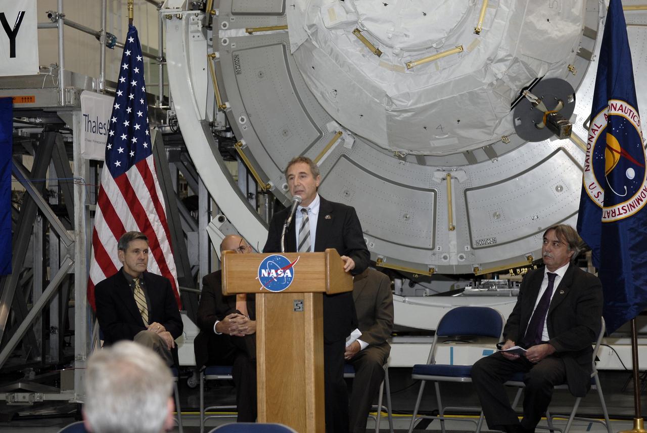 CAPE CANAVERAL, Fla. – In the Space Station Processing Facility at NASA's Kennedy Space Center in Florida, Bernardo Patti, head of International Space Station, Program Department, ESA, addresses the invited guests at a ceremony transferring the ownership of node 3 for the International Space Station, looming in the background, from the European Space Agency, or ESA, to NASA.  Seated, from left, are Bob Cabana, Kennedy Space Center director, and Secondino Brondolo, head of the Space Infrastructure, Thales Alenia Space Italy.    Node 3 is named "Tranquility" after the Sea of Tranquility, the lunar landing site of Apollo 11.  The payload for the STS-130 mission, Tranquility is a pressurized module that will provide room for many of the International Space Station's life support systems. The module was built for ESA by Thales Alenia Space in Turin, Italy. Attached to one end of Tranquility is a cupola, a unique work station with six windows on its sides and one on top.  The cupola resembles a circular bay window and will provide a vastly improved view of the station's exterior. Just under 10 feet in diameter, the module will accommodate two crew members and portable workstations that can control station and robotic activities. The multi-directional view will allow the crew to monitor spacewalks and docking operations, as well as provide a spectacular view of Earth and other celestial objects. Space shuttle Endeavour's STS-130 mission is targeted to launch Feb. 4, 2010. Photo credit: NASA/Kim Shiflett
