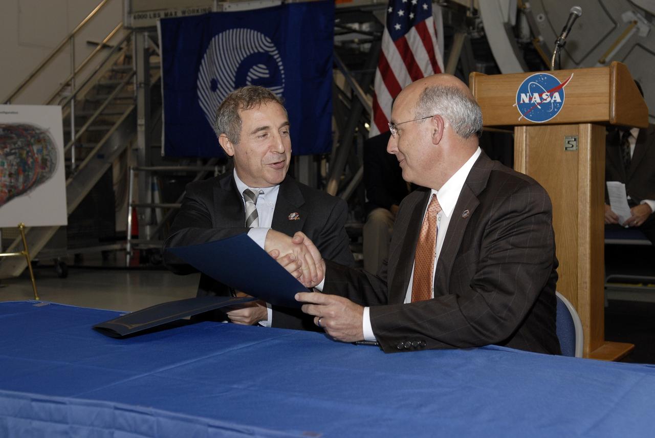 CAPE CANAVERAL, Fla. – In the Space Station Processing Facility at NASA's Kennedy Space Center in Florida, Bernardo Patti, at left, head of International Space Station, Program Department, European Space Agency, congratulates Michael Suffredini, program manager, International Space Station, NASA, upon transfer of the ownership of node 3 for the International Space Station from the European Space Agency, or ESA, to NASA.    Node 3 is named "Tranquility" after the Sea of Tranquility, the lunar landing site of Apollo 11.  The payload for the STS-130 mission, Tranquility is a pressurized module that will provide room for many of the International Space Station's life support systems. The module was built for ESA by Thales Alenia Space in Turin, Italy. Attached to one end of Tranquility is a cupola, a unique work station with six windows on its sides and one on top.  The cupola resembles a circular bay window and will provide a vastly improved view of the station's exterior. Just under 10 feet in diameter, the module will accommodate two crew members and portable workstations that can control station and robotic activities. The multi-directional view will allow the crew to monitor spacewalks and docking operations, as well as provide a spectacular view of Earth and other celestial objects. Space shuttle Endeavour's STS-130 mission is targeted to launch Feb. 4, 2010. Photo credit: NASA/Kim Shiflett