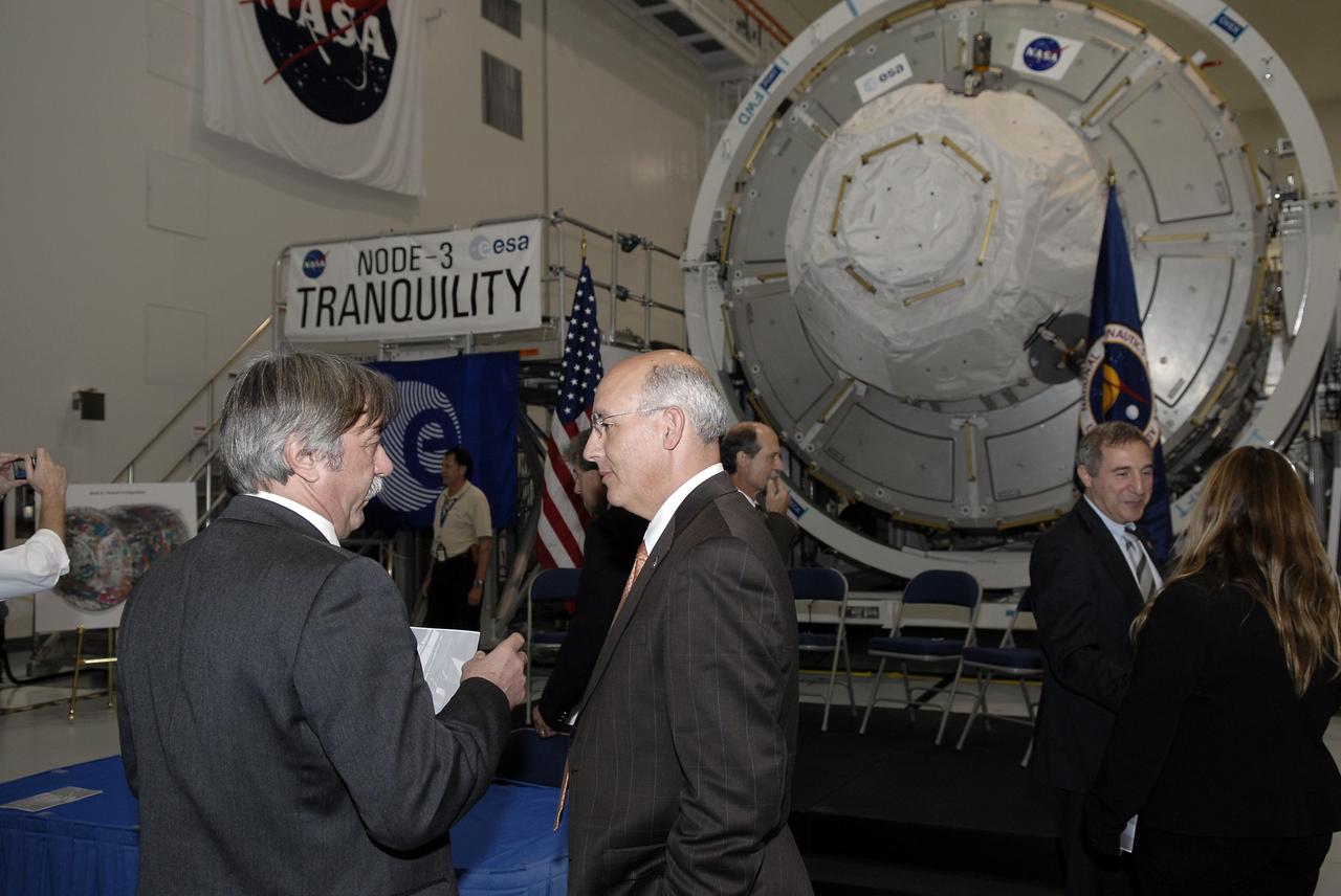 CAPE CANAVERAL, Fla. – In the Space Station Processing Facility at NASA's Kennedy Space Center in Florida, Secondino Brondolo, at left, head of the Space Infrastructure, Thales Alenia Space Italy, talks to Michael Suffredini, program manager, International Space Station, NASA, following a ceremony transferring the ownership of node 3 for the International Space Station from the European Space Agency, or ESA, to NASA.    Node 3 is named "Tranquility" after the Sea of Tranquility, the lunar landing site of Apollo 11.  The payload for the STS-130 mission, Tranquility is a pressurized module that will provide room for many of the International Space Station's life support systems. The module was built for ESA by Thales Alenia Space in Turin, Italy. Attached to one end of Tranquility is a cupola, a unique work station with six windows on its sides and one on top.  The cupola resembles a circular bay window and will provide a vastly improved view of the station's exterior. Just under 10 feet in diameter, the module will accommodate two crew members and portable workstations that can control station and robotic activities. The multi-directional view will allow the crew to monitor spacewalks and docking operations, as well as provide a spectacular view of Earth and other celestial objects. Space shuttle Endeavour's STS-130 mission is targeted to launch Feb. 4, 2010. Photo credit: NASA/Kim Shiflett