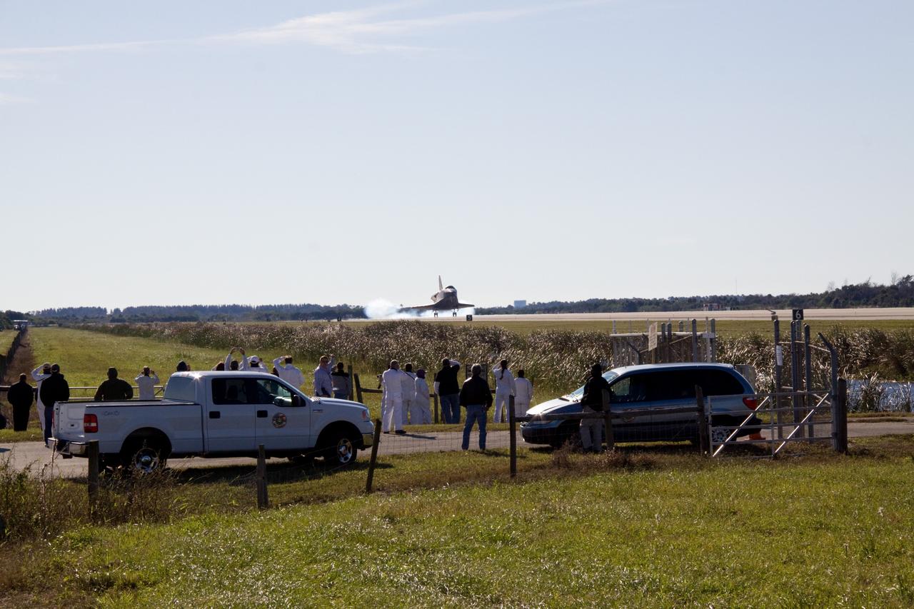 CAPE CANAVERAL, Fla. - Space shuttle Atlantis kicks up dust as it touches down on Runway 33 at the Shuttle Landing Facility at NASA's Kennedy Space Center in Florida with convoy workers waiting for the appropriate time to join it on the runway.  After 11 days in space, Atlantis completed the 4.5-million mile STS-129 mission on orbit 171.    Main gear touchdown was at 9:44:23 a.m. EST. Nose gear touchdown was at 9:44:36 a.m., and wheels stop was at 9:45:05 a.m. Aboard Atlantis are Commander Charles O. Hobaugh; Pilot Barry E. Wilmore; Mission Specialists Leland Melvin, Randy Bresnik, Mike Foreman and Robert L. Satcher Jr.; and Expedition 20 and 21 Flight Engineer Nicole Stott who spent 87 days aboard the International Space Station. STS-129 is the final space shuttle Expedition crew rotation flight on the manifest. On STS-129, the crew delivered 14 tons of cargo to the orbiting laboratory, including two ExPRESS Logistics Carriers containing spare parts to sustain station operations after the shuttles are retired next year. For information on the STS-129 mission and crew, visit http://www.nasa.gov/mission_pages/shuttle/shuttlemissions/sts129/index.html. Photo credit: NASA/Jack Pfaller