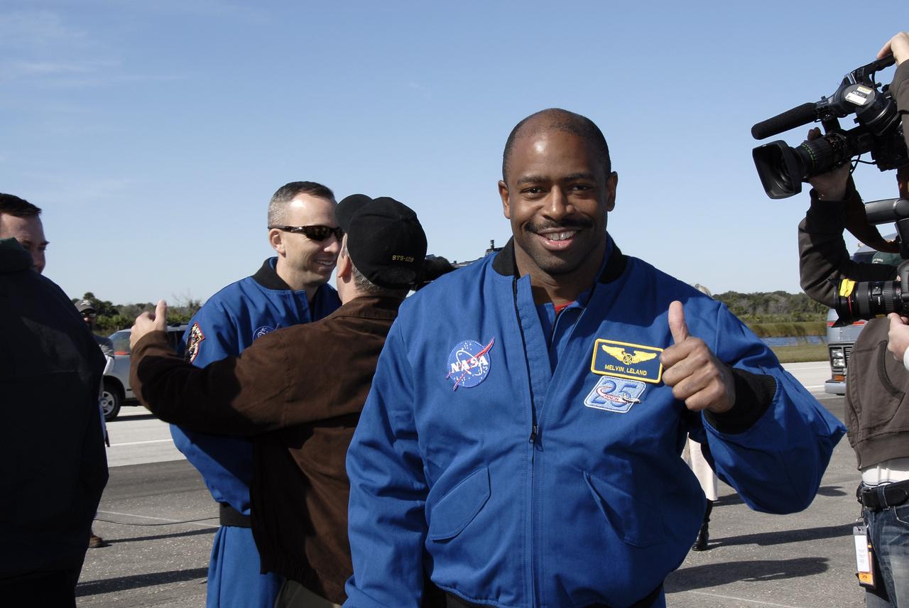 CAPE CANAVERAL, Fla. - At the Shuttle Landing Facility at NASA's Kennedy Space Center in Florida, STS-129 Mission Specialist Leland Melvin gives the camera a thumbs up following the landing of space shuttle Atlantis, concluding his successful 11-day mission. In the background, fellow crewmate Randy Bresnik, wearing sunglasses, talks with a well-wisher. Space shuttle Atlantis landed on Runway 33, completing the 4.5-million-mile STS-129 mission to the International Space Station on orbit 171. Main gear touchdown was at 9:44:23 a.m. EST. Nose gear touchdown was at 9:44:36 a.m., and wheels stop was at 9:45:05 a.m. On STS-129, the six-member crew delivered 14 tons of cargo to the orbiting laboratory, including two ExPRESS Logistics Carriers containing spare parts to sustain station operations after the shuttles are retired next year. For information on the STS-129 mission and crew, visit http://www.nasa.gov/mission_pages/shuttle/shuttlemissions/sts129/index.html. Photo credit: NASA/Kim Shiflett