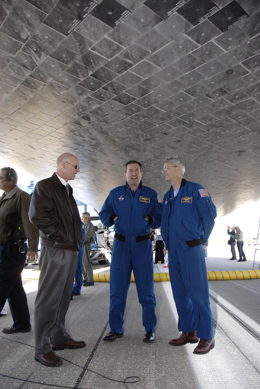 CAPE CANAVERAL, Fla. - Standing under space shuttle Atlantis at the Shuttle Landing Facility at NASA's Kennedy Space Center in Florida, STS-129 NASA Test Director Steve Payne, left, discusses the newly completed mission with STS-129 Mission Specialist Mike Foreman, center, and NASA pilot Dick Clark.  Atlantis touched down on Runway 33, completing the 4.5-million-mile STS-129 mission on orbit 171.  Main gear touchdown was at 9:44:23 a.m. EST. Nose gear touchdown was at 9:44:36 a.m., and wheels stop was at 9:45:05 a.m.  On STS-129, the six-member crew delivered 14 tons of cargo to the orbiting laboratory, including two ExPRESS Logistics Carriers containing spare parts to sustain station operations after the shuttles are retired next year.  For information on the STS-129 mission and crew, visit http://www.nasa.gov/mission_pages/shuttle/shuttlemissions/sts129/index.html.    Photo credit: NASA/Kim Shiflett
