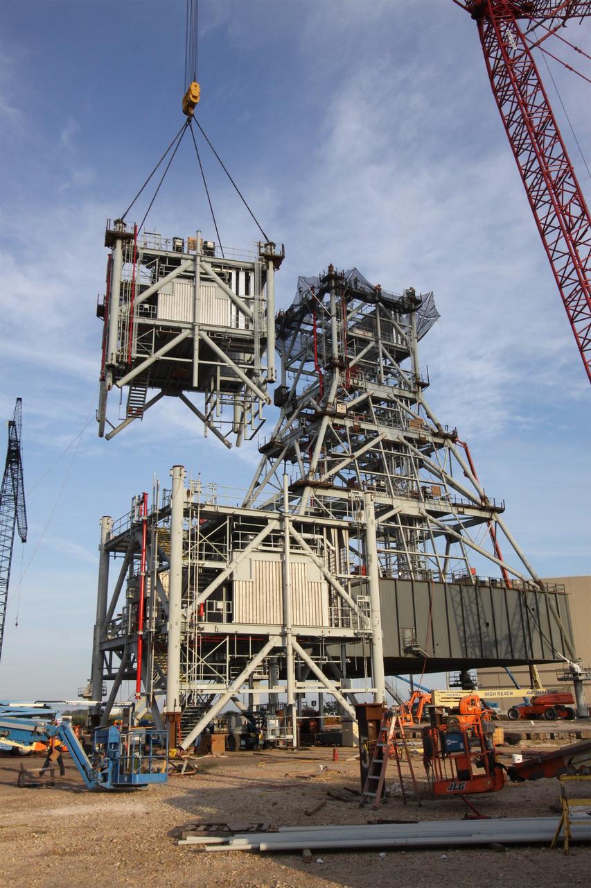 CAPE CANAVERAL, Fla. – At NASA's Kennedy Space Center in Florida, a crane lifts a fifth tower segment toward four segments already secured to a new mobile launcher, or ML, being constructed to support the Constellation Program. When completed, the tower will be approximately 345 feet tall and have multiple platforms for personnel access. The construction is under way at the mobile launcher park site area north of Kennedy's Vehicle Assembly Building. The launcher will provide a base to launch the Ares I rocket, designed to transport the Orion crew exploration vehicle, its crew and cargo to low Earth orbit. Its base is being made lighter than space shuttle mobile launcher platforms so the crawler-transporter can pick up the heavier load of the tower and taller rocket. For information on the Ares I, visit http://www.nasa.gov/ares. Photo credit: NASA/Jack Pfaller