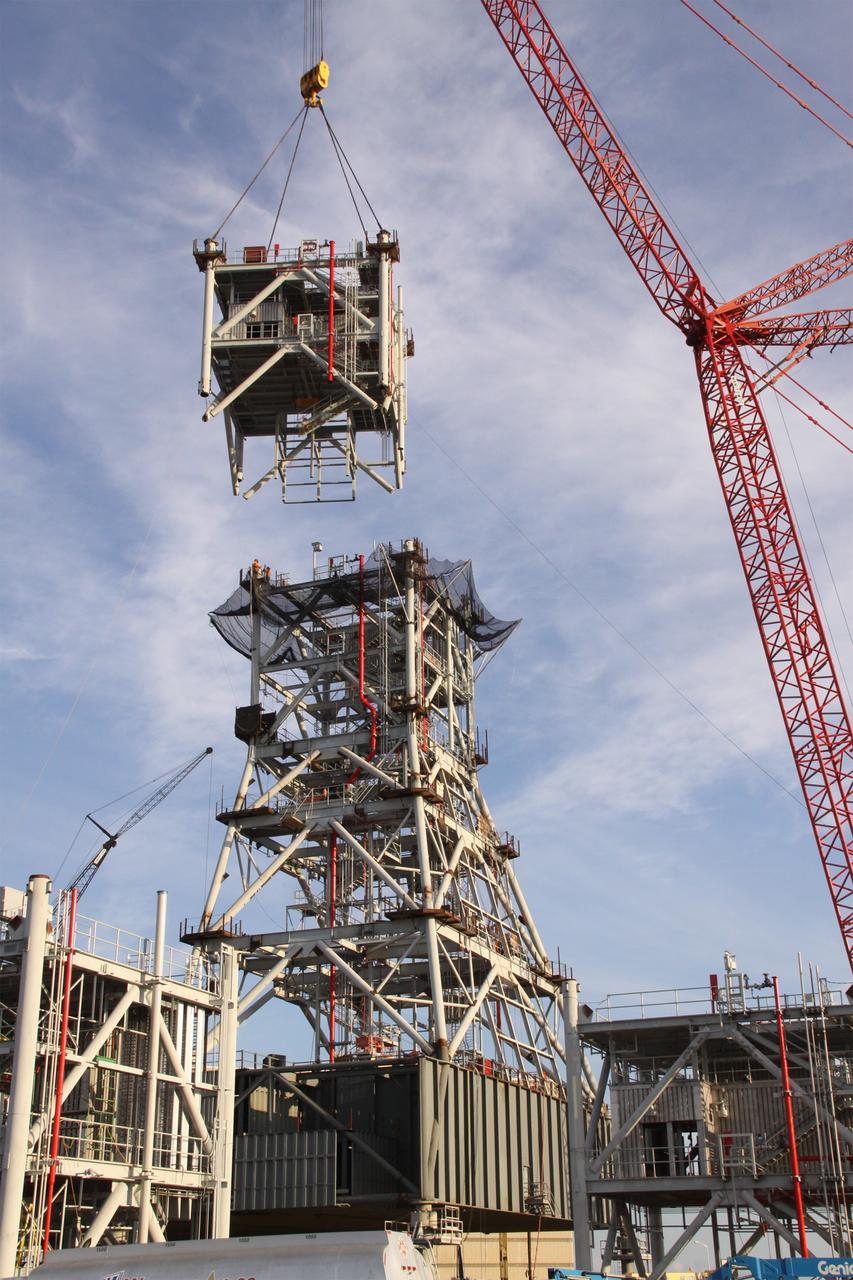 CAPE CANAVERAL, Fla. – At NASA's Kennedy Space Center in Florida, a crane lowers a fifth tower segment onto four segments already secured to a new mobile launcher, or ML, being constructed to support the Constellation Program. When completed, the tower will be approximately 345 feet tall and have multiple platforms for personnel access. The construction is under way at the mobile launcher park site area north of Kennedy's Vehicle Assembly Building. The launcher will provide a base to launch the Ares I rocket, designed to transport the Orion crew exploration vehicle, its crew and cargo to low Earth orbit. Its base is being made lighter than space shuttle mobile launcher platforms so the crawler-transporter can pick up the heavier load of the tower and taller rocket. For information on the Ares I, visit http://www.nasa.gov/ares. Photo credit: NASA/Jack Pfaller