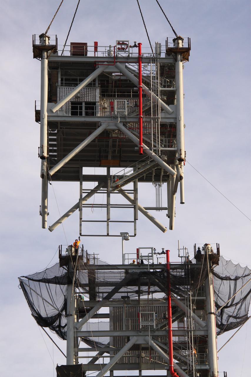 CAPE CANAVERAL, Fla. – At NASA's Kennedy Space Center in Florida, workers await the delivery of the fifth tower segment atop the tower segments already secured on a new mobile launcher, or ML, being constructed to support the Constellation Program. When completed, the tower will be approximately 345 feet tall and have multiple platforms for personnel access. The construction is under way at the mobile launcher park site area north of Kennedy's Vehicle Assembly Building. The launcher will provide a base to launch the Ares I rocket, designed to transport the Orion crew exploration vehicle, its crew and cargo to low Earth orbit. Its base is being made lighter than space shuttle mobile launcher platforms so the crawler-transporter can pick up the heavier load of the tower and taller rocket. For information on the Ares I, visit http://www.nasa.gov/ares. Photo credit: NASA/Jack Pfaller