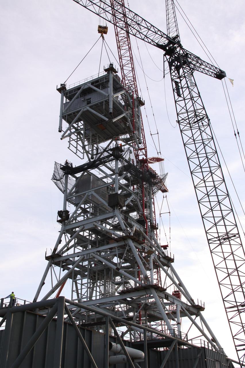 CAPE CANAVERAL, Fla. – At NASA's Kennedy Space Center in Florida, a crane positions a fifth tower segment onto four segments already secured to a new mobile launcher, or ML, being constructed to support the Constellation Program. When completed, the tower will be approximately 345 feet tall and have multiple platforms for personnel access. The construction is under way at the mobile launcher park site area north of Kennedy's Vehicle Assembly Building. The launcher will provide a base to launch the Ares I rocket, designed to transport the Orion crew exploration vehicle, its crew and cargo to low Earth orbit. Its base is being made lighter than space shuttle mobile launcher platforms so the crawler-transporter can pick up the heavier load of the tower and taller rocket. For information on the Ares I, visit http://www.nasa.gov/ares. Photo credit: NASA/Jack Pfaller