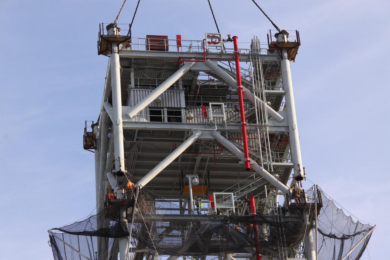 CAPE CANAVERAL, Fla. – At NASA's Kennedy Space Center in Florida, workers prepare to secure the fifth tower segment to the tower rising on a new mobile launcher, or ML, being constructed to support the Constellation Program. When completed, the tower will be approximately 345 feet tall and have multiple platforms for personnel access. The construction is under way at the mobile launcher park site area north of Kennedy's Vehicle Assembly Building. The launcher will provide a base to launch the Ares I rocket, designed to transport the Orion crew exploration vehicle, its crew and cargo to low Earth orbit. Its base is being made lighter than space shuttle mobile launcher platforms so the crawler-transporter can pick up the heavier load of the tower and taller rocket. For information on the Ares I, visit http://www.nasa.gov/ares. Photo credit: NASA/Jack Pfaller