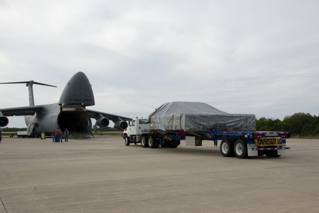 CAPE CANAVERAL, Fla. - At the Shuttle Landing Facility at NASA's Kennedy Space Center in Florida, the ExPRESS Logistics Carrier 3, or ELC-3, is secured on the bed of the truck which will transport it to the Space Station Processing Facility. At left is the U.S. Air Force C-5 aircraft on which it arrived. ELC-3 and the Alpha Magnetic Spectrometer are the primary payloads for space shuttle Endeavour's STS-134 mission to the International Space Station. The STS-134 crew will also deliver spare parts including two S-band communications antennas, a high pressure gas tank, additional spare parts for Dextre and micrometeoroid debris shields. Endeavour's launch is targeted for July 29, 2010. For information on the STS-134 mission objectives and crew, visit http://www.nasa.gov/shuttle. Photo credit: NASA/Kim Shiflett