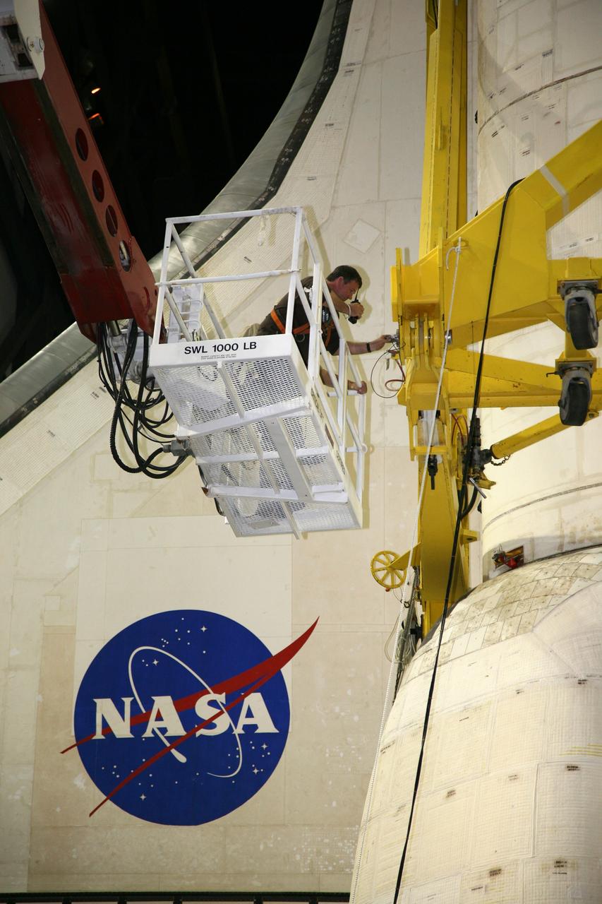 CAPE CANAVERAL, Fla. – In the transfer aisle of the Vehicle Assembly Building at NASA's Kennedy Space Center in Florida, a United Space Alliance technician communicates with his co-workers regarding the readiness of space shuttle Endeavour to be lifted.    Next, Endeavour will be hoisted over a transom and lowered into High Bay 1, where it will be attached to its external fuel tank and solid rocket boosters. Rollout of the shuttle stack to Kennedy’s Launch Pad 39A, a significant milestone in launch processing activities, is planned for early January 2010. The Italian-built Tranquility module, the primary payload for Endeavour's STS-130 mission, will be installed in the payload bay after the shuttle arrives at the pad.  Launch is targeted for early February. For information on the STS-130 mission and crew, visit http://www.nasa.gov/mission_pages/shuttle/shuttlemissions/sts130/index.html.  Photo credit: NASA/Dimitri Gerondidakis