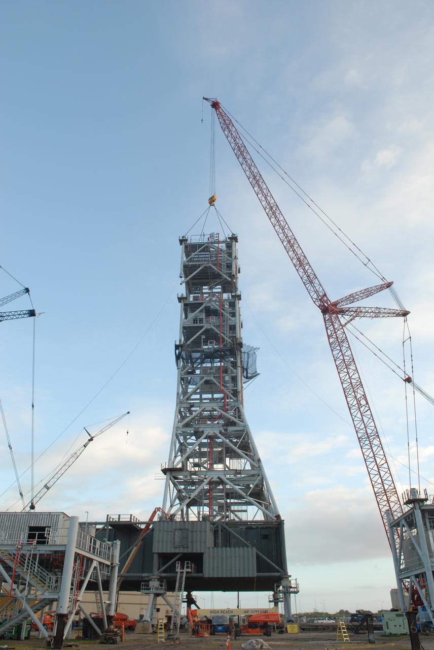 CAPE CANAVERAL, Fla. – At NASA's Kennedy Space Center in Florida, a crane positions a sixth tower segment onto five segments already secured to a new mobile launcher, or ML, being constructed to support the Constellation Program. When completed, the tower will be approximately 345 feet tall and have multiple platforms for personnel access. The construction is under way at the mobile launcher park site area north of Kennedy's Vehicle Assembly Building. The launcher will provide a base to launch the Ares I rocket, designed to transport the Orion crew exploration vehicle, its crew and cargo to low Earth orbit. Its base is being made lighter than space shuttle mobile launcher platforms so the crawler-transporter can pick up the heavier load of the tower and taller rocket. For information on the Ares I, visit http://www.nasa.gov/ares. Photo credit: NASA/Jim Grossmann