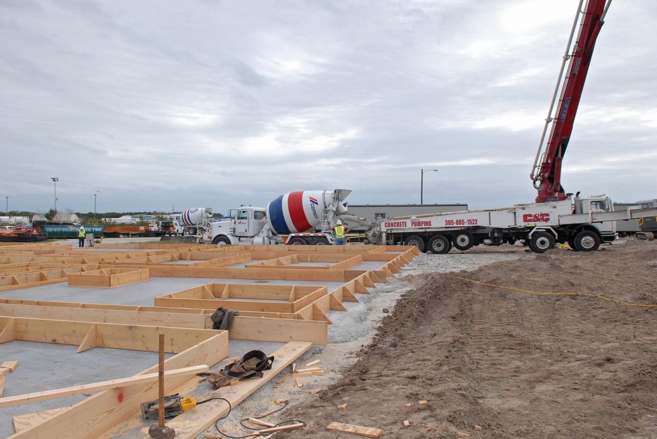 CAPE CANAVERAL, Fla. - Construction of the walls for the Propellants North Administrative and Maintenance Facility begins in Launch Complex 39 at NASA's Kennedy Space Center in Florida.    A tilt-up construction method is being used to erect a THERMOMASS concrete wall insulation system for the facility's walls.  In this approach, the exterior layer of concrete for the wall panels is poured and leveled on the building's footprint. Then, prefabricated, predrilled insulation sheets are arranged on top of the unhardened concrete, and connectors, designed to hold the sandwiched layers of concrete and insulation secure, are inserted through the predrilled holes. Next, the structural wythe is poured.  Once cured, these panels are lifted upright to form the building's envelope.  The facility will have a two-story administrative building to house managers, mechanics and technicians who fuel spacecraft at Kennedy adjacent to an 1,800-square-foot single-story shop to store cryogenic fuel transfer equipment.  The new facility will feature high-efficiency roofs and walls, “Cool Dry Quiet” air conditioning with energy recovery technology, efficient lighting, and other sustainable features. The facility is striving to qualify for the U.S. Green Building Council’s Leadership in Energy and Environmental Design, or LEED, Platinum certification. If successful, Propellants North will be the first Kennedy facility to achieve this highest of LEED ratings after it is completed in the summer of 2010.  The facility was designed for NASA by Jones Edmunds and Associates.  Photo credit: NASA/Jim Grossmann
