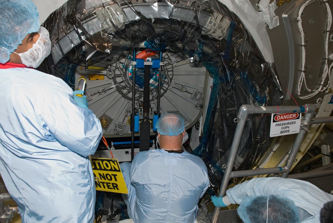 CAPE CANAVERAL, Fla. – In the Space Station Processing Facility at NASA's Kennedy Space Center in Florida, workers dressed in clean room attire, known as bunny suits, begin to shut the hatch on the International Space Station's Node 3, named Tranquility.    Hatch closure follows the completion of preparations for the node's transport to the pad and is a significant milestone in launch processing activities. The primary payload for the STS-130 mission, Tranquility is a pressurized module that will provide room for many of the space station's life support systems. Attached to one end of Tranquility is a cupola, a unique work area with six windows on its sides and one on top.  The cupola resembles a circular bay window and will provide a vastly improved view of the station's exterior. The multi-directional view will allow the crew to monitor spacewalks and docking operations, as well as provide a spectacular view of Earth and other celestial objects. The module was built in Turin, Italy, by Thales Alenia Space for the European Space Agency.  Space shuttle Endeavour's STS-130 mission is targeted for launch in early February 2010. For information on the STS-130 mission and crew, visit http://www.nasa.gov/mission_pages/shuttle/shuttlemissions/sts130/index.html.  Photo credit: NASA/Jim Grossmann
