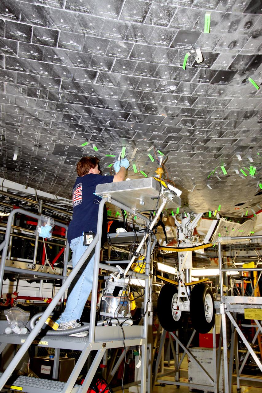 CAPE CANAVERAL, Fla. - In Orbiter Processing Facility Bay 1 at NASA's Kennedy Space Center in Florida, United Space Alliance technician Jeff Holmes makes a putty repair on some of the high-temperature reusable surface insulation tiles, or HRSI tiles, on the lower forward fuselage of space shuttle Atlantis. An average of 125 tiles are replaced after each mission either due to handling damage or accumulated repairs. These black tiles are optimized for maximum emissivity, which means they lose heat faster than white tiles. This property is required to maximize heat rejection during the hot phase of reentry. Atlantis next is slated to deliver an Integrated Cargo Carrier and Russian-built Mini Research Module to the International Space Station on the STS-132 mission. Launch is targeted for May 14, 2010. Photo credit: NASA/Jack Pfaller