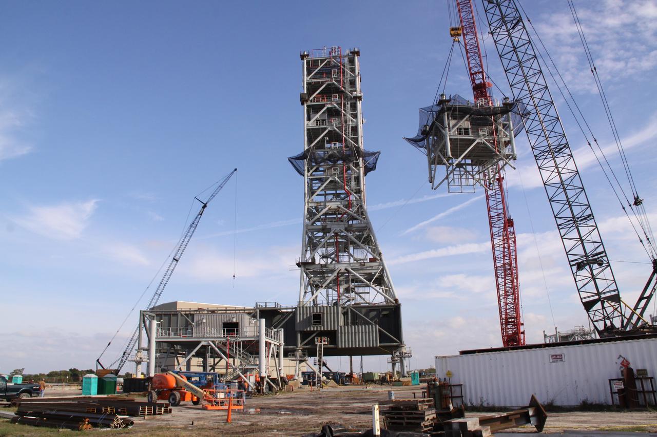 CAPE CANAVERAL, Fla. – At NASA's Kennedy Space Center in Florida, the seventh tower segment of a new mobile launcher, or ML, being constructed to support the Constellation Program, is hoisted by crane toward the six segments already secured to the launcher's surface. When completed, the tower will be approximately 345 feet tall and have multiple platforms for personnel access. The construction is under way at the mobile launcher park site area north of Kennedy's Vehicle Assembly Building. The launcher will provide a base to launch the Ares I rocket, designed to transport the Orion crew exploration vehicle, its crew and cargo to low Earth orbit. Its base is being made lighter than space shuttle mobile launcher platforms so the crawler-transporter can pick up the heavier load of the tower and taller rocket. For information on the Ares I, visit http://www.nasa.gov/ares. Photo credit: NASA/Jack Pfaller