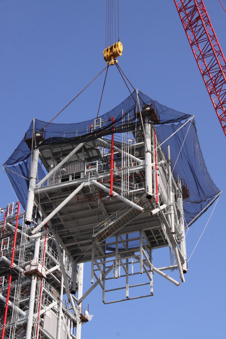 CAPE CANAVERAL, Fla. – At NASA's Kennedy Space Center in Florida, a crane maneuvers the seventh tower segment of a new mobile launcher, or ML, being constructed to support the Constellation Program, toward the six segments already in place, in the background at left. When completed, the tower will be approximately 345 feet tall and have multiple platforms for personnel access. The construction is under way at the mobile launcher park site area north of Kennedy's Vehicle Assembly Building. The launcher will provide a base to launch the Ares I rocket, designed to transport the Orion crew exploration vehicle, its crew and cargo to low Earth orbit. Its base is being made lighter than space shuttle mobile launcher platforms so the crawler-transporter can pick up the heavier load of the tower and taller rocket. For information on the Ares I, visit http://www.nasa.gov/ares. Photo credit: NASA/Jack Pfaller