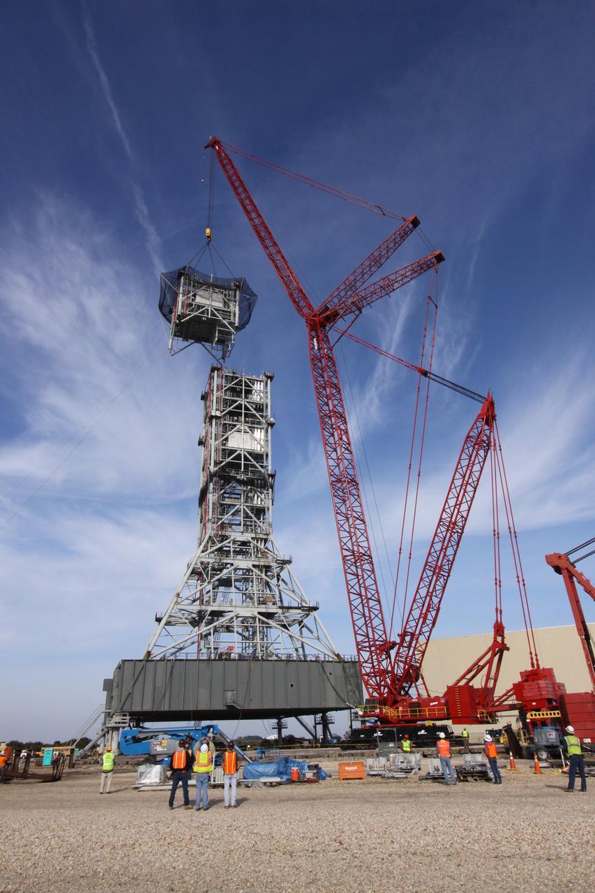 CAPE CANAVERAL, Fla. – At NASA's Kennedy Space Center in Florida, a crane slowly eases the seventh tower segment of a new mobile launcher, or ML, being constructed to support the Constellation Program, into position over the six segments already secured to the launcher's surface.    When completed, the tower will be approximately 345 feet tall and have multiple platforms for personnel access. The construction is under way at the mobile launcher park site area north of Kennedy's Vehicle Assembly Building. The launcher will provide a base to launch the Ares I rocket, designed to transport the Orion crew exploration vehicle, its crew and cargo to low Earth orbit. Its base is being made lighter than space shuttle mobile launcher platforms so the crawler-transporter can pick up the heavier load of the tower and taller rocket.  For information on the Ares I, visit http://www.nasa.gov/ares. Photo credit: NASA/Jack Pfaller