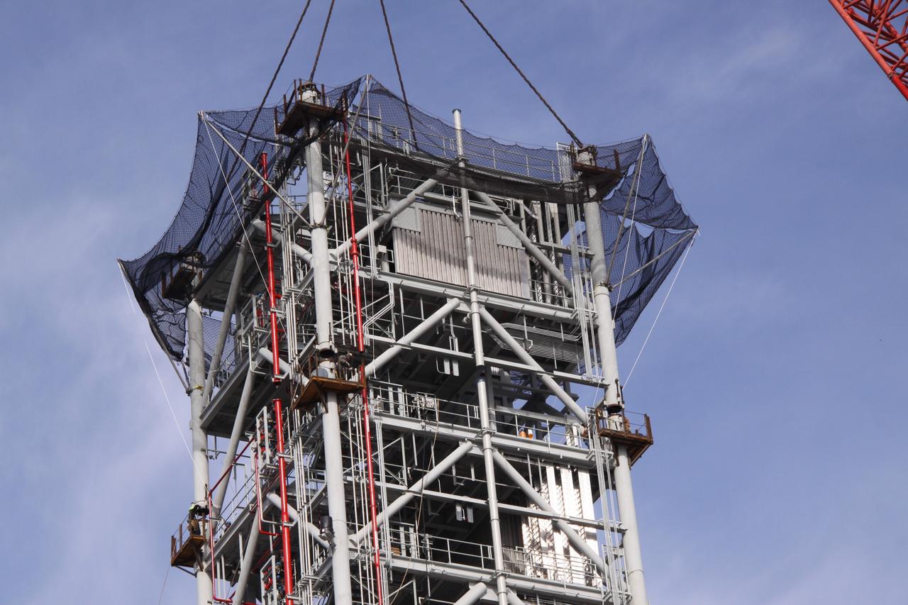 CAPE CANAVERAL, Fla. – At NASA's Kennedy Space Center in Florida, the seventh tower segment of a new mobile launcher, or ML, being constructed to support the Constellation Program, is lined up with the six segments already secured to the launcher's surface.    When completed, the tower will be approximately 345 feet tall and have multiple platforms for personnel access. The construction is under way at the mobile launcher park site area north of Kennedy's Vehicle Assembly Building. The launcher will provide a base to launch the Ares I rocket, designed to transport the Orion crew exploration vehicle, its crew and cargo to low Earth orbit. Its base is being made lighter than space shuttle mobile launcher platforms so the crawler-transporter can pick up the heavier load of the tower and taller rocket.  For information on the Ares I, visit http://www.nasa.gov/ares. Photo credit: NASA/Jack Pfaller
