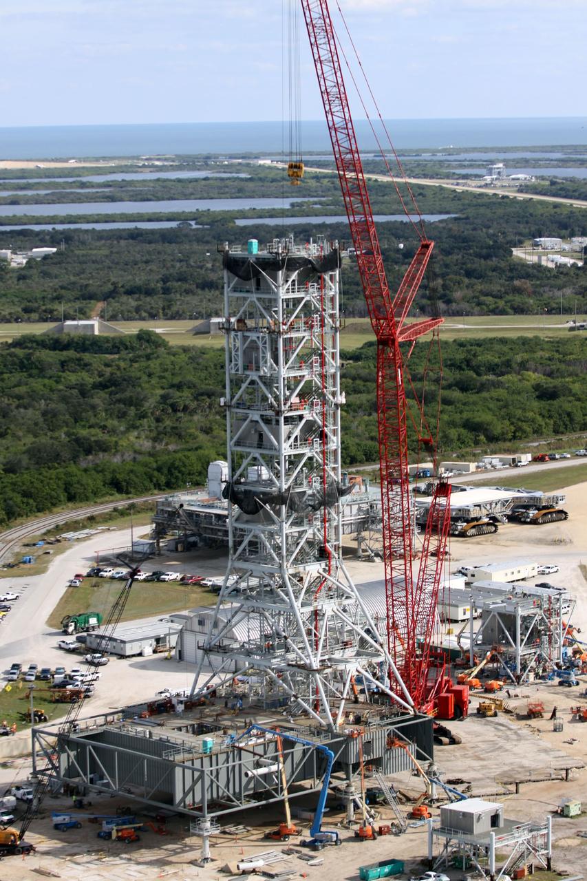 CAPE CANAVERAL, Fla. – At NASA's Kennedy Space Center in Florida, this aerial view of the mobile launcher park site area north of the 525-foot-tall Vehicle Assembly Building shows a new mobile launcher, or ML, for the Constellation Program under construction.  In the background are the Atlantic Ocean and the Launch Complex 39 Observation Gantry, at upper right.    When completed, the tower will be approximately 345 feet tall and have multiple platforms for personnel access. Its base is being made lighter than space shuttle mobile launcher platforms so the crawler-transporter can pick up the heavier load of the tower and a taller rocket.  For information on the Constellation Program, visit http://www.nasa.gov/constellation. Photo credit: NASA/Cory Huston