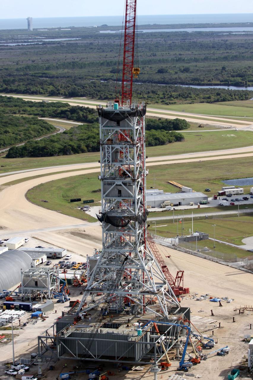 CAPE CANAVERAL, Fla. – At NASA's Kennedy Space Center in Florida, this aerial view of the mobile launcher park site area north of the 525-foot-tall Vehicle Assembly Building shows a new mobile launcher, or ML, for the Constellation Program under construction.  In the background are the Atlantic Ocean and Launch Complex 41 on Cape Canaveral Air Force Station, at upper left, from which Atlas V rockets are launched.    When completed, the tower will be approximately 345 feet tall and have multiple platforms for personnel access. Its base is being made lighter than space shuttle mobile launcher platforms so the crawler-transporter can pick up the heavier load of the tower and a taller rocket.  For information on the Constellation Program, visit http://www.nasa.gov/constellation. Photo credit: NASA/Cory Huston