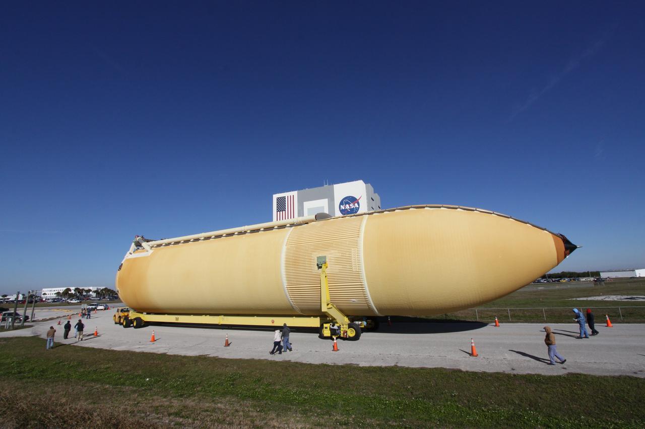 CAPE CANAVERAL, Fla. – At NASA's Kennedy Space Center in Florida, workers accompany External Tank-135 as it is transported to the Vehicle Assembly Building in the background. The tank arrived in Florida on Dec. 26 aboard the Pegasus barge, towed by a solid rocket booster retrieval ship from NASA's Michoud Assembly Facility near New Orleans. ET-135 will be used to launch space shuttle Discovery on the STS-131 mission to the International Space Station. Launch is targeted for March 18. For information on the components of the space shuttle and the STS-131 mission, visit http://www.nasa.gov/mission_pages/shuttle/shuttlemissions/sts131/index.html. Photo credit: NASA/Jack Pfaller