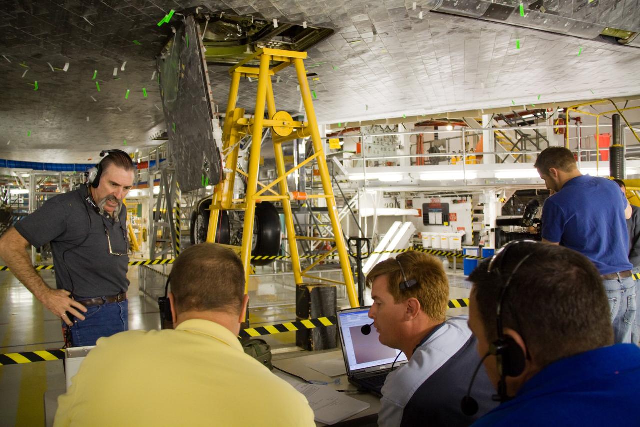 CAPE CANAVERAL, Fla. - In Orbiter Processing Facility 1 at NASA's Kennedy Space Center in Florida, United Space Alliance technicians study the results of a push test performed on an external tank door on space shuttle Atlantis.    Two umbilical doors, located on the shuttle's aft fuselage, close after external tank separation following launch. The test confirms that the door's actuators are functioning properly and that signals sent from the actuators correctly indicate that the doors have closed, creating the necessary thermal barrier for reentry.  Atlantis is next slated to deliver an Integrated Cargo Carrier and Russian-built Mini Research Module to the International Space Station on the STS-132 mission.  The second in a series of new pressurized components for Russia, the module will be permanently attached to the Zarya module. Three spacewalks are planned to store spare components outside the station, including six spare batteries, a boom assembly for the Ku-band antenna and spares for the Canadian Dextre robotic arm extension. A radiator, airlock and European robotic arm for the Russian Multi-purpose Laboratory Module also are payloads on the flight.  Launch is targeted for May 14, 2010.  Photo credit: NASA/Troy Cryder