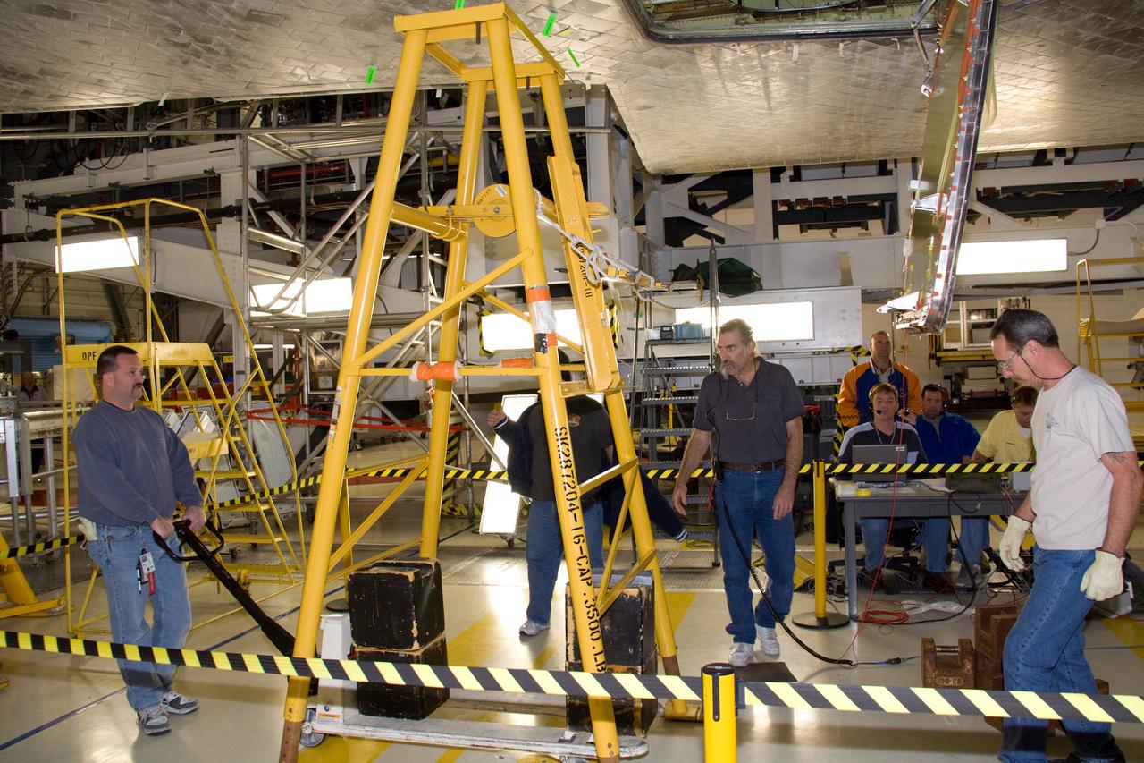 CAPE CANAVERAL, Fla. - In Orbiter Processing Facility 1 at NASA's Kennedy Space Center in Florida, United Space Alliance technicians roll the test equipment away from an external tank door on space shuttle Atlantis following the successful completion of a push test.    Two umbilical doors, located on the shuttle's aft fuselage, close after external tank separation following launch. The test confirms that the door's actuators are functioning properly and that signals sent from the actuators correctly indicate that the doors have closed, creating the necessary thermal barrier for reentry.  Atlantis is next slated to deliver an Integrated Cargo Carrier and Russian-built Mini Research Module to the International Space Station on the STS-132 mission.  The second in a series of new pressurized components for Russia, the module will be permanently attached to the Zarya module. Three spacewalks are planned to store spare components outside the station, including six spare batteries, a boom assembly for the Ku-band antenna and spares for the Canadian Dextre robotic arm extension. A radiator, airlock and European robotic arm for the Russian Multi-purpose Laboratory Module also are payloads on the flight.  Launch is targeted for May 14, 2010.  Photo credit: NASA/Troy Cryder
