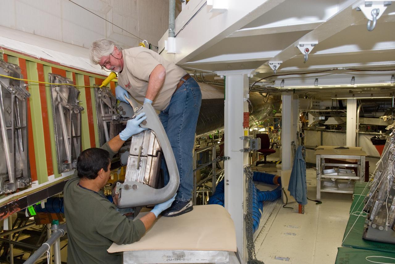 CAPE CANAVERAL, Fla. - In Orbiter Processing Facility-1 at NASA's Kennedy Space Center in Florida, United Space Alliance technicians remove a reinforced carbon carbon panel, or RCC panel, from a wing leading edge of space shuttle Atlantis.    Inspection and maintenance of the RCC panels and the wing leading edge are standard procedure between shuttle missions.  The RCC panels, components of the shuttle's thermal protection system, are placed in protective coverings while the structural edge of the wing -- the orange and green area behind the panels -- undergoes spar corrosion inspection to verify the structural integrity of the wing. Atlantis is next slated to deliver an Integrated Cargo Carrier and Russian-built Mini Research Module to the International Space Station on the STS-132 mission.  The second in a series of new pressurized components for Russia, the module will be permanently attached to the Zarya module. Three spacewalks are planned to store spare components outside the station, including six spare batteries, a boom assembly for the Ku-band antenna and spares for the Canadian Dextre robotic arm extension. A radiator, airlock and European robotic arm for the Russian Multi-purpose Laboratory Module also are payloads on the flight.  Launch is targeted for May 14, 2010.  Photo credit: NASA/Glenn Benson