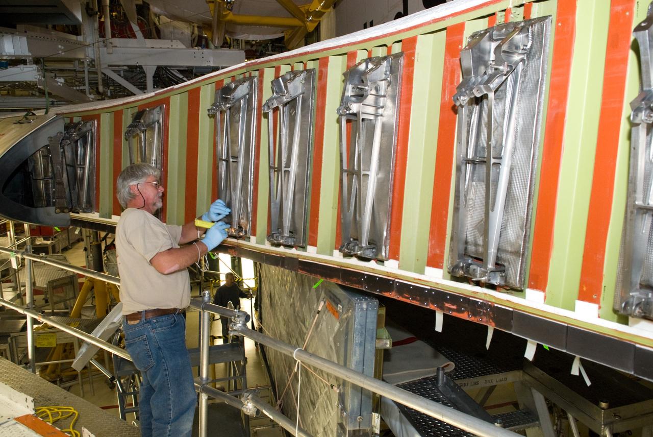 CAPE CANAVERAL, Fla. - In Orbiter Processing Facility-1 at NASA's Kennedy Space Center in Florida, a United Space Alliance technician inspects a wing leading edge of space shuttle Atlantis following removal of the reinforced carbon carbon panels, or RCC panels.    Inspection and maintenance of the RCC panels and the wing leading edge are standard procedure between shuttle missions.  The RCC panels, components of the shuttle's thermal protection system, are placed in protective coverings while the structural edge of the wing -- the orange and green area behind the panels -- undergoes spar corrosion inspection to verify the structural integrity of the wing. Atlantis is next slated to deliver an Integrated Cargo Carrier and Russian-built Mini Research Module to the International Space Station on the STS-132 mission.  The second in a series of new pressurized components for Russia, the module will be permanently attached to the Zarya module. Three spacewalks are planned to store spare components outside the station, including six spare batteries, a boom assembly for the Ku-band antenna and spares for the Canadian Dextre robotic arm extension. A radiator, airlock and European robotic arm for the Russian Multi-purpose Laboratory Module also are payloads on the flight.  Launch is targeted for May 14, 2010.  Photo credit: NASA/Glenn Benson
