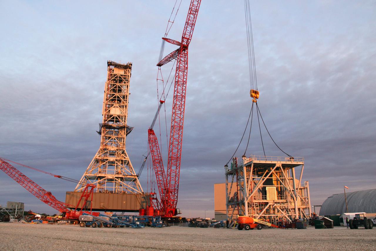 CAPE CANAVERAL, Fla. – Sunrise over NASA's Kennedy Space Center in Florida reveals preparations under way to install the eighth tower segment on a new mobile launcher, or ML, being constructed to support the Constellation Program. When completed, the tower will be approximately 345 feet tall and have multiple platforms for personnel access. The construction is under way at the mobile launcher park site area north of Kennedy's Vehicle Assembly Building. The launcher will provide a base to launch the Ares I rocket, designed to transport the Orion crew exploration vehicle, its crew and cargo to low Earth orbit. Its base is being made lighter than space shuttle mobile launcher platforms so the crawler-transporter can pick up the heavier load of the tower and taller rocket. For information on the Ares I, visit http://www.nasa.gov/ares. Photo credit: NASA/Troy Cryder