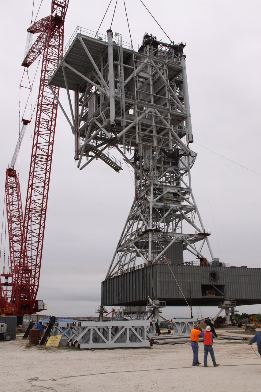 CAPE CANAVERAL, Fla. – At NASA's Kennedy Space Center in Florida, a crane hoists the eighth tower segment of a new mobile launcher, or ML, being constructed to support the Constellation Program, off the ground toward the launcher's growing tower. When completed, the tower will be approximately 345 feet tall and have multiple platforms for personnel access. The construction is under way at the mobile launcher park site area north of Kennedy's Vehicle Assembly Building. The launcher will provide a base to launch the Ares I rocket, designed to transport the Orion crew exploration vehicle, its crew and cargo to low Earth orbit. Its base is being made lighter than space shuttle mobile launcher platforms so the crawler-transporter can pick up the heavier load of the tower and taller rocket. For information on the Ares I, visit http://www.nasa.gov/ares. Photo credit: NASA/Jack Pfaller