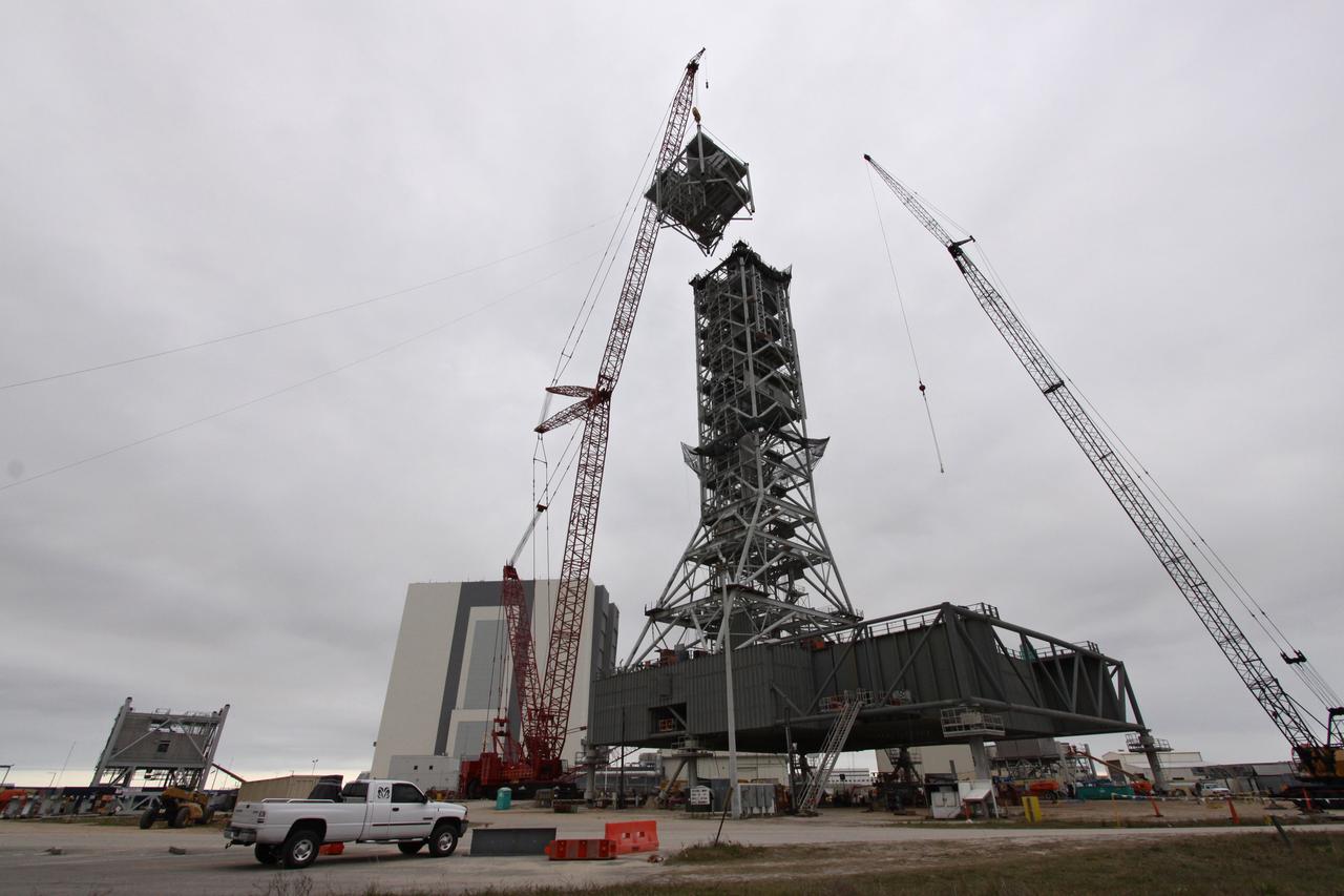 CAPE CANAVERAL, Fla. – At NASA's Kennedy Space Center in Florida, a crane gently lowers an eighth tower segment toward the seven segments previously secured to a new mobile launcher, or ML, being constructed to support the Constellation Program. When completed, the tower will be approximately 345 feet tall and have multiple platforms for personnel access. The construction is under way at the mobile launcher park site area north of Kennedy's Vehicle Assembly Building. The launcher will provide a base to launch the Ares I rocket, designed to transport the Orion crew exploration vehicle, its crew and cargo to low Earth orbit. Its base is being made lighter than space shuttle mobile launcher platforms so the crawler-transporter can pick up the heavier load of the tower and taller rocket. For information on the Ares I, visit http://www.nasa.gov/ares. Photo credit: NASA/Jack Pfaller