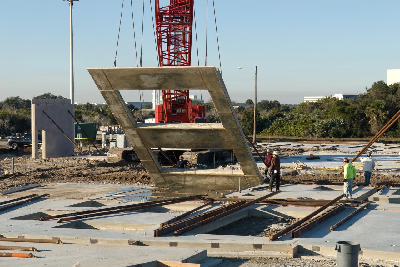 CAPE CANAVERAL, Fla. - In Launch Complex 39 at NASA's Kennedy Space Center in Florida, workers lift one of the walls of the Propellants North Administrative and Maintenance Facility into an upright position.    A tilt-up construction method is being used to erect a THERMOMASS concrete wall insulation system for the facility's walls.  In this approach, the exterior layer of concrete for the wall panels is poured and leveled on the building's footprint. Then, prefabricated, predrilled insulation sheets are arranged on top of the unhardened concrete, and connectors, designed to hold the sandwiched layers of concrete and insulation secure, are inserted through the predrilled holes. Next, the structural wythe is poured.  Once cured, these panels are lifted upright to form the building's envelope.  The facility will have a two-story administrative building to house managers, mechanics and technicians who fuel spacecraft at Kennedy adjacent to an 1,800-square-foot single-story shop to store cryogenic fuel transfer equipment.  The new facility will feature high-efficiency roofs and walls, “Cool Dry Quiet” air conditioning with energy recovery technology, efficient lighting, and other sustainable features. The facility is striving to qualify for the U.S. Green Building Council’s Leadership in Energy and Environmental Design, or LEED, Platinum certification. If successful, Propellants North will be the first Kennedy facility to achieve this highest of LEED ratings after it is completed in the summer of 2010.  The facility was designed for NASA by Jones Edmunds and Associates.  Photo credit: NASA/Jim Grossmann