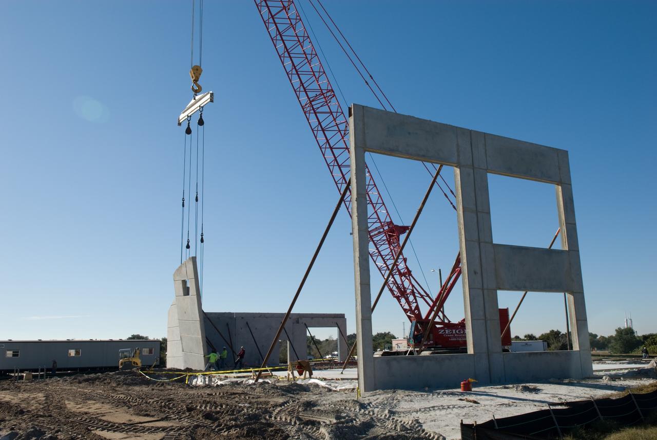 CAPE CANAVERAL, Fla. - In Launch Complex 39 at NASA's Kennedy Space Center in Florida, the Propellants North Administrative and Maintenance Facility begins to take shape as its walls are lifted into position.    A tilt-up construction method is being used to erect a THERMOMASS concrete wall insulation system for the facility's walls.  In this approach, the exterior layer of concrete for the wall panels is poured and leveled on the building's footprint. Then, prefabricated, predrilled insulation sheets are arranged on top of the unhardened concrete, and connectors, designed to hold the sandwiched layers of concrete and insulation secure, are inserted through the predrilled holes. Next, the structural wythe is poured.  Once cured, these panels are lifted upright to form the building's envelope.  The facility will have a two-story administrative building to house managers, mechanics and technicians who fuel spacecraft at Kennedy adjacent to an 1,800-square-foot single-story shop to store cryogenic fuel transfer equipment.  The new facility will feature high-efficiency roofs and walls, “Cool Dry Quiet” air conditioning with energy recovery technology, efficient lighting, and other sustainable features. The facility is striving to qualify for the U.S. Green Building Council’s Leadership in Energy and Environmental Design, or LEED, Platinum certification. If successful, Propellants North will be the first Kennedy facility to achieve this highest of LEED ratings after it is completed in the summer of 2010.  The facility was designed for NASA by Jones Edmunds and Associates.  Photo credit: NASA/Jim Grossmann