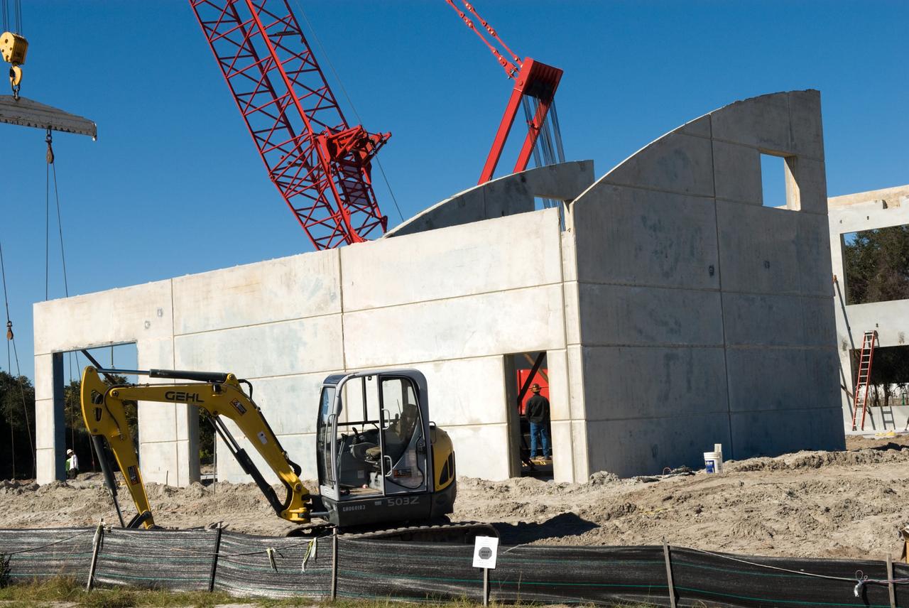 CAPE CANAVERAL, Fla. - In Launch Complex 39 at NASA's Kennedy Space Center in Florida, a worker is seen through an opening left for a doorway in a newly erected wall of the Propellants North Administrative and Maintenance Facility.    A tilt-up construction method is being used to erect a THERMOMASS concrete wall insulation system for the facility's walls.  In this approach, the exterior layer of concrete for the wall panels is poured and leveled on the building's footprint. Then, prefabricated, predrilled insulation sheets are arranged on top of the unhardened concrete, and connectors, designed to hold the sandwiched layers of concrete and insulation secure, are inserted through the predrilled holes. Next, the structural wythe is poured.  Once cured, these panels are lifted upright to form the building's envelope.  The facility will have a two-story administrative building to house managers, mechanics and technicians who fuel spacecraft at Kennedy adjacent to an 1,800-square-foot single-story shop to store cryogenic fuel transfer equipment.  The new facility will feature high-efficiency roofs and walls, “Cool Dry Quiet” air conditioning with energy recovery technology, efficient lighting, and other sustainable features. The facility is striving to qualify for the U.S. Green Building Council’s Leadership in Energy and Environmental Design, or LEED, Platinum certification. If successful, Propellants North will be the first Kennedy facility to achieve this highest of LEED ratings after it is completed in the summer of 2010.  The facility was designed for NASA by Jones Edmunds and Associates.  Photo credit: NASA/Jim Grossmann