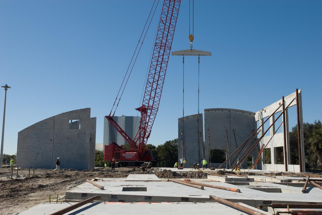 CAPE CANAVERAL, Fla. - The 525-foot-tall Vehicle Assembly Building, in the background, is witness to the formation of the Propellants North Administrative and Maintenance Facility, a new "green" building under construction in Launch Complex 39 at NASA's Kennedy Space Center in Florida.  Concrete layers on either side of high-density foam insulation in the facility's walls will prevent any transfer of radiant heat between the exterior and interior of the buildings.    A tilt-up construction method is being used to erect a THERMOMASS concrete wall insulation system for the facility's walls.  In this approach, the exterior layer of concrete for the wall panels is poured and leveled on the building's footprint. Then, prefabricated, predrilled insulation sheets are arranged on top of the unhardened concrete, and connectors, designed to hold the sandwiched layers of concrete and insulation secure, are inserted through the predrilled holes. Next, the structural wythe is poured.  Once cured, these panels are lifted upright to form the building's envelope.  The facility will have a two-story administrative building to house managers, mechanics and technicians who fuel spacecraft at Kennedy adjacent to an 1,800-square-foot single-story shop to store cryogenic fuel transfer equipment.  The new facility will feature high-efficiency roofs and walls, “Cool Dry Quiet” air conditioning with energy recovery technology, efficient lighting, and other sustainable features. The facility is striving to qualify for the U.S. Green Building Council’s Leadership in Energy and Environmental Design, or LEED, Platinum certification. If successful, Propellants North will be the first Kennedy facility to achieve this highest of LEED ratings after it is completed in the summer of 2010.  The facility was designed for NASA by Jones Edmunds and Associates.  Photo credit: NASA/Jim Grossmann