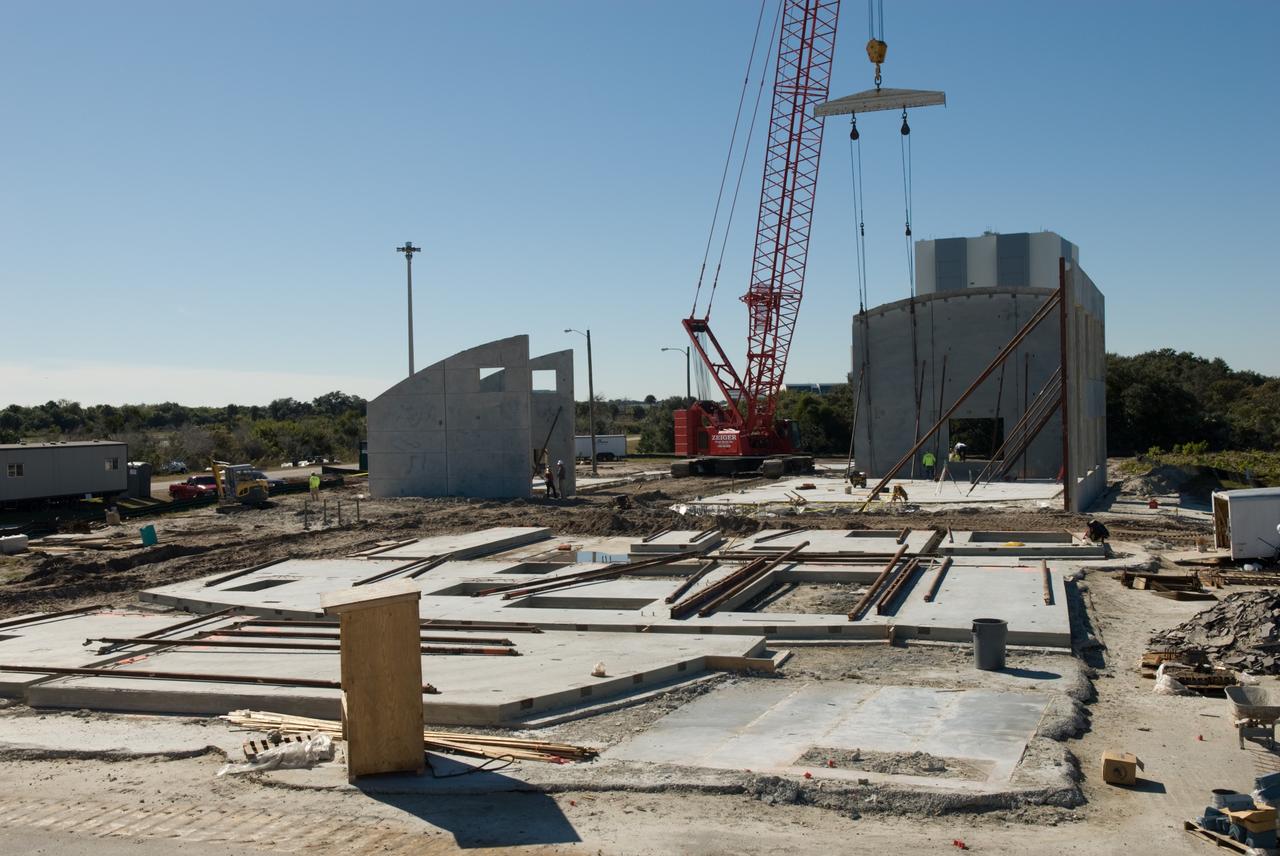 CAPE CANAVERAL, Fla. - In Launch Complex 39 at NASA's Kennedy Space Center in Florida, a crane is enlisted to lift the walls of the Propellants North Administrative and Maintenance Facility into position.    A tilt-up construction method is being used to erect a THERMOMASS concrete wall insulation system for the facility's walls.  In this approach, the exterior layer of concrete for the wall panels is poured and leveled on the building's footprint. Then, prefabricated, predrilled insulation sheets are arranged on top of the unhardened concrete, and connectors, designed to hold the sandwiched layers of concrete and insulation secure, are inserted through the predrilled holes. Next, the structural wythe is poured.  Once cured, these panels are lifted upright to form the building's envelope.  The facility will have a two-story administrative building to house managers, mechanics and technicians who fuel spacecraft at Kennedy adjacent to an 1,800-square-foot single-story shop to store cryogenic fuel transfer equipment.  The new facility will feature high-efficiency roofs and walls, “Cool Dry Quiet” air conditioning with energy recovery technology, efficient lighting, and other sustainable features. The facility is striving to qualify for the U.S. Green Building Council’s Leadership in Energy and Environmental Design, or LEED, Platinum certification. If successful, Propellants North will be the first Kennedy facility to achieve this highest of LEED ratings after it is completed in the summer of 2010.  The facility was designed for NASA by Jones Edmunds and Associates.  Photo credit: NASA/Jim Grossmann